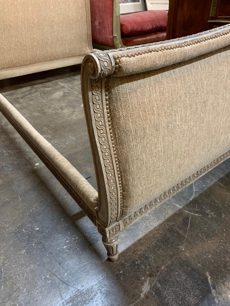 Beautiful French Louis XVI style carved upholstered bed. Very fine carvings on this piece and it is upholstered in a pretty woven beige fabric. Makes an elegant statement!
