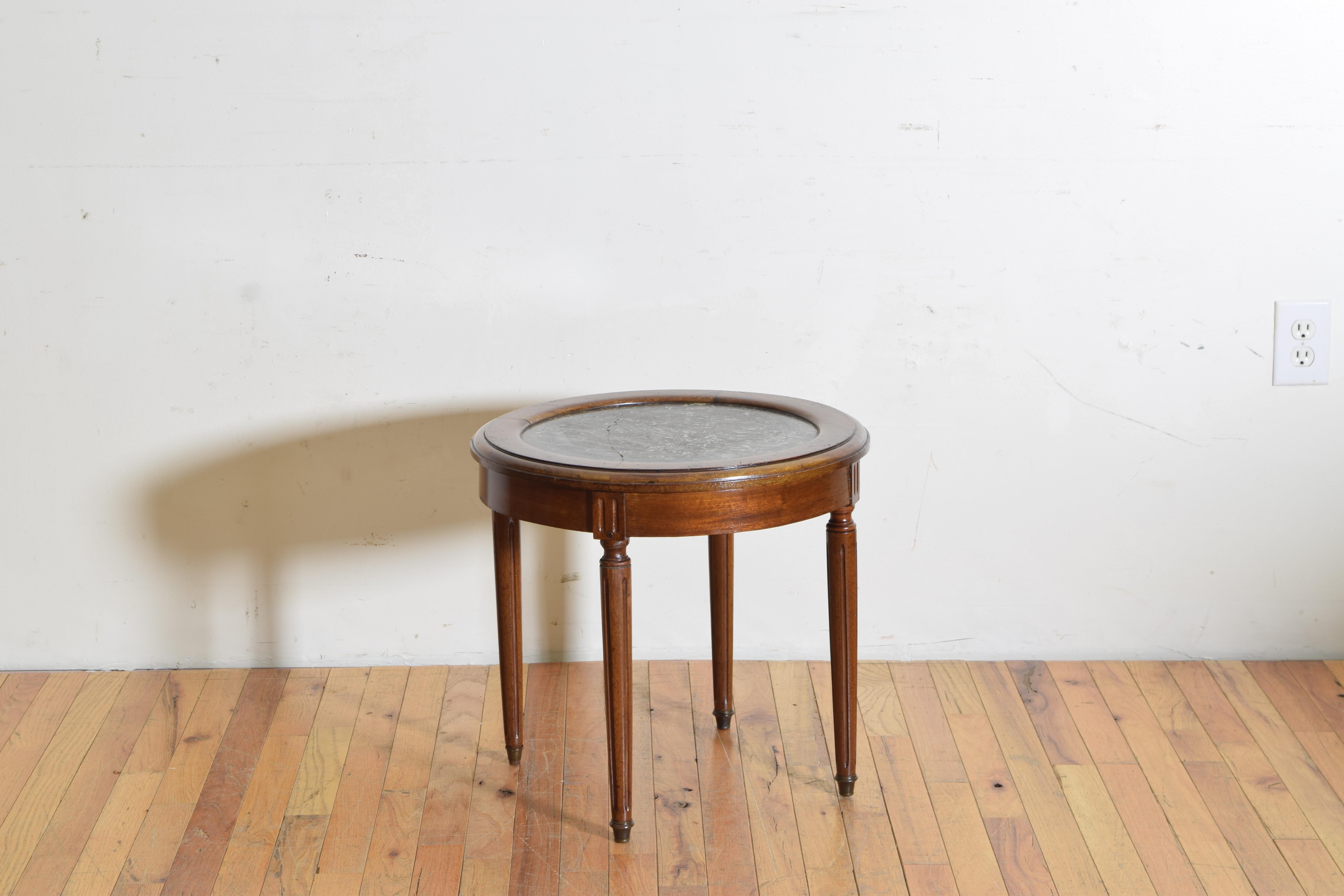 The circular top with a raised edge and inset marble top, the apron with fluting and raised on circular fluted legs ending in brass casters.