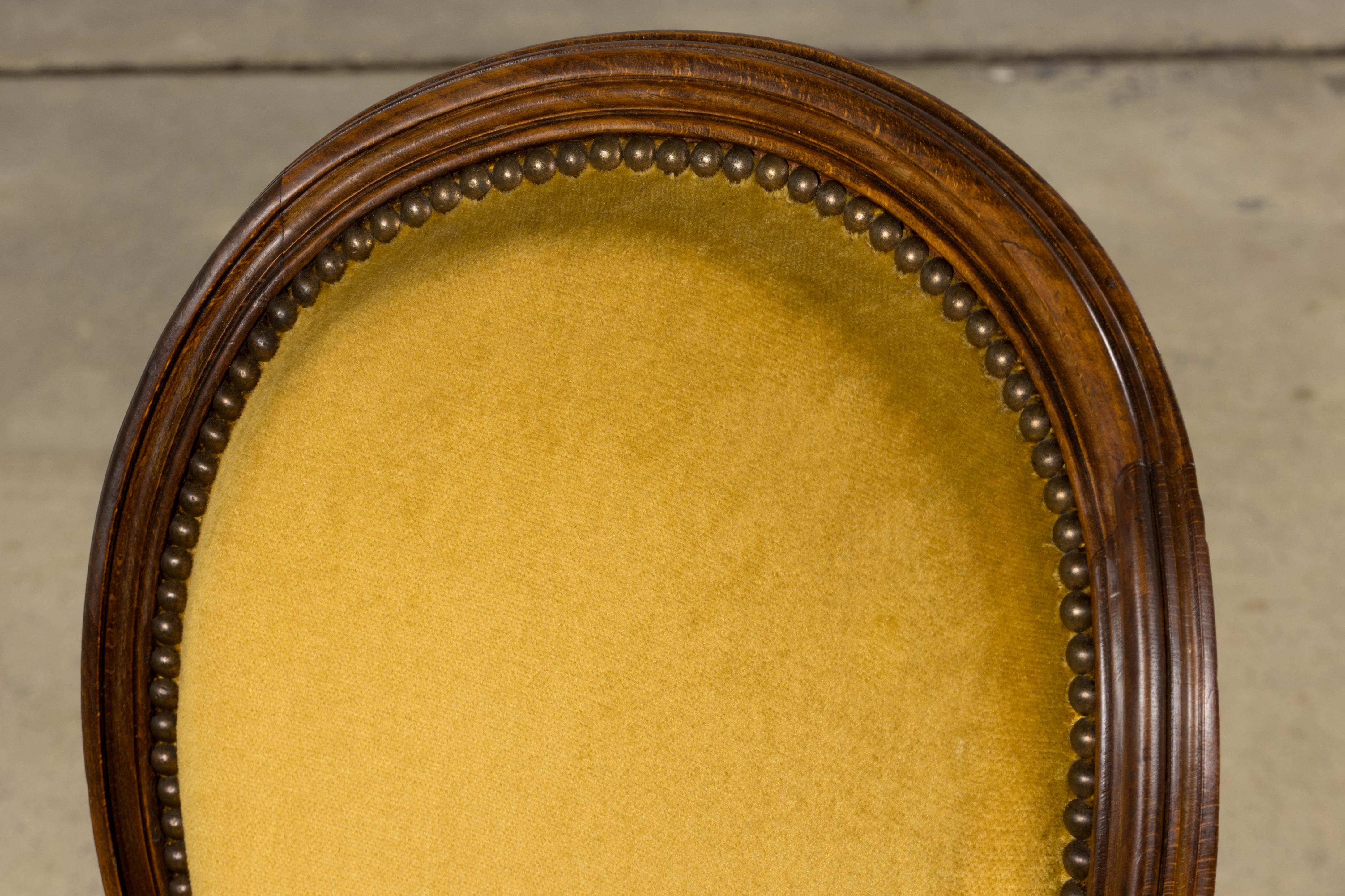 Chaise d'appoint de style Louis XVI française du début du 20e siècle, provenant de Provence. La chaise présente un élégant dossier ovale, des rosettes florales sculptées à la main dans les coins et des pieds cannelés classiques, caractéristiques de