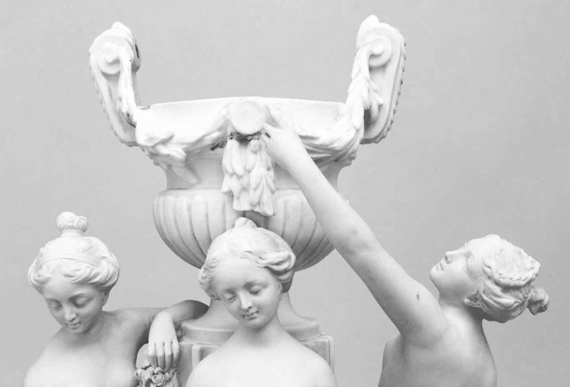 French Louis XVI-style (late 19th Century) white biscuit porcelain centerpiece with the Three Graces standing around an garland hung urn on a fluted column
