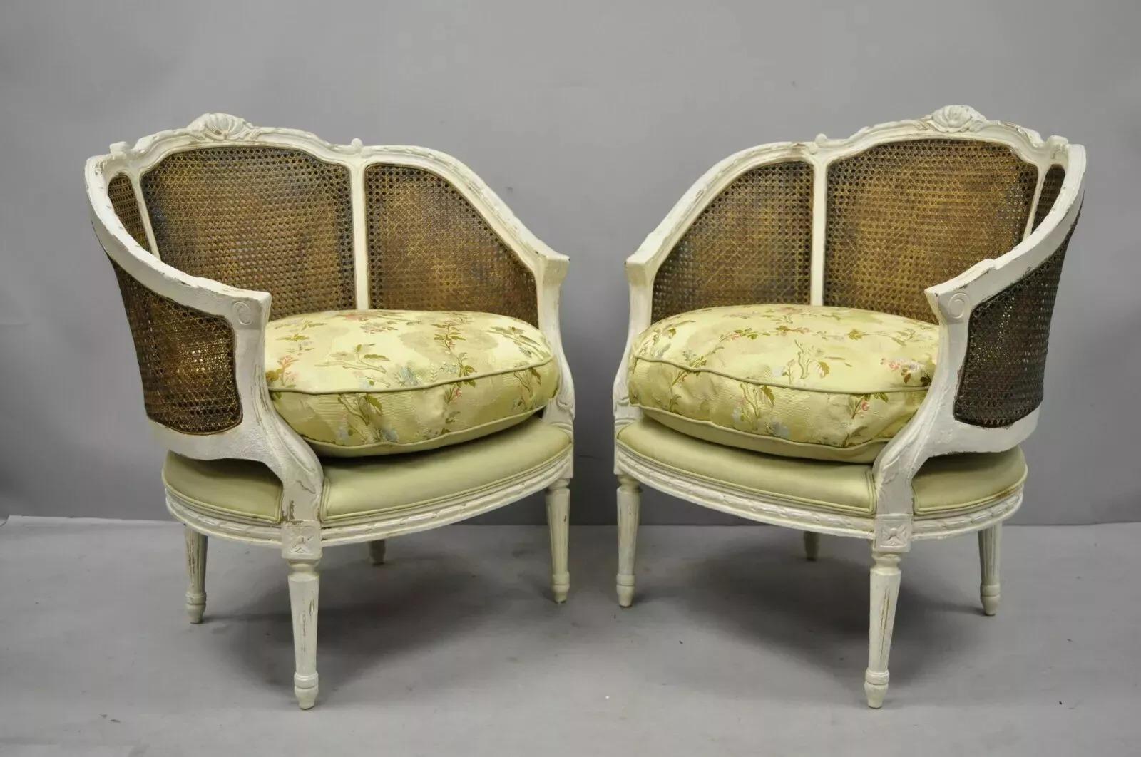 Pareja de sillones bergere de caña pintados en blanco de estilo Luis XVI. El artículo tiene respaldo de caña, acabado pintado en blanco envejecido, cojines sueltos, construcción de madera maciza, patas cónicas, gran estilo y forma. Mediados del