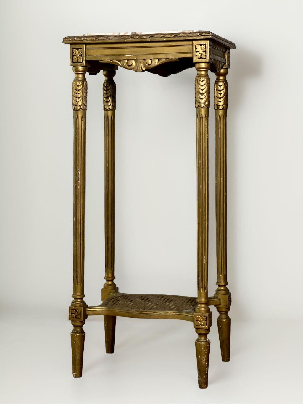 Antique early 20th century French Louis XVI style giltwood rectangular pedestal stand with marble top and lower cane tier. Tall and elegant, this stand has a white and gray fitted marble top edged by twisted ribbon detail above an apron with corner