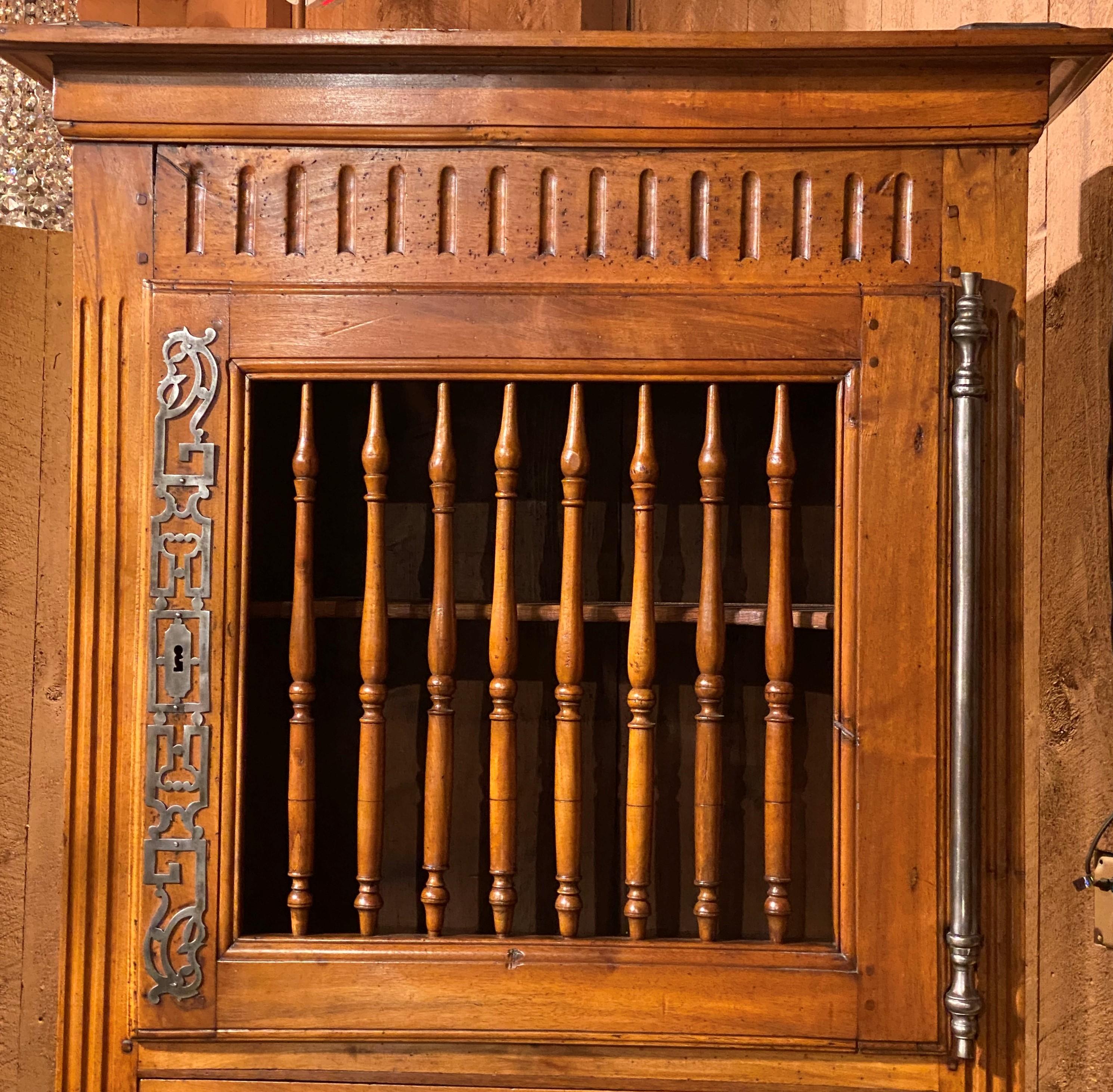 A fine French Louis XVI walnut two door armoire with removable molded cornice, its top panetière style door with turned spindle open panel window, opening to a single interior shaped adjustable shelf , over a single drawer which separates it from