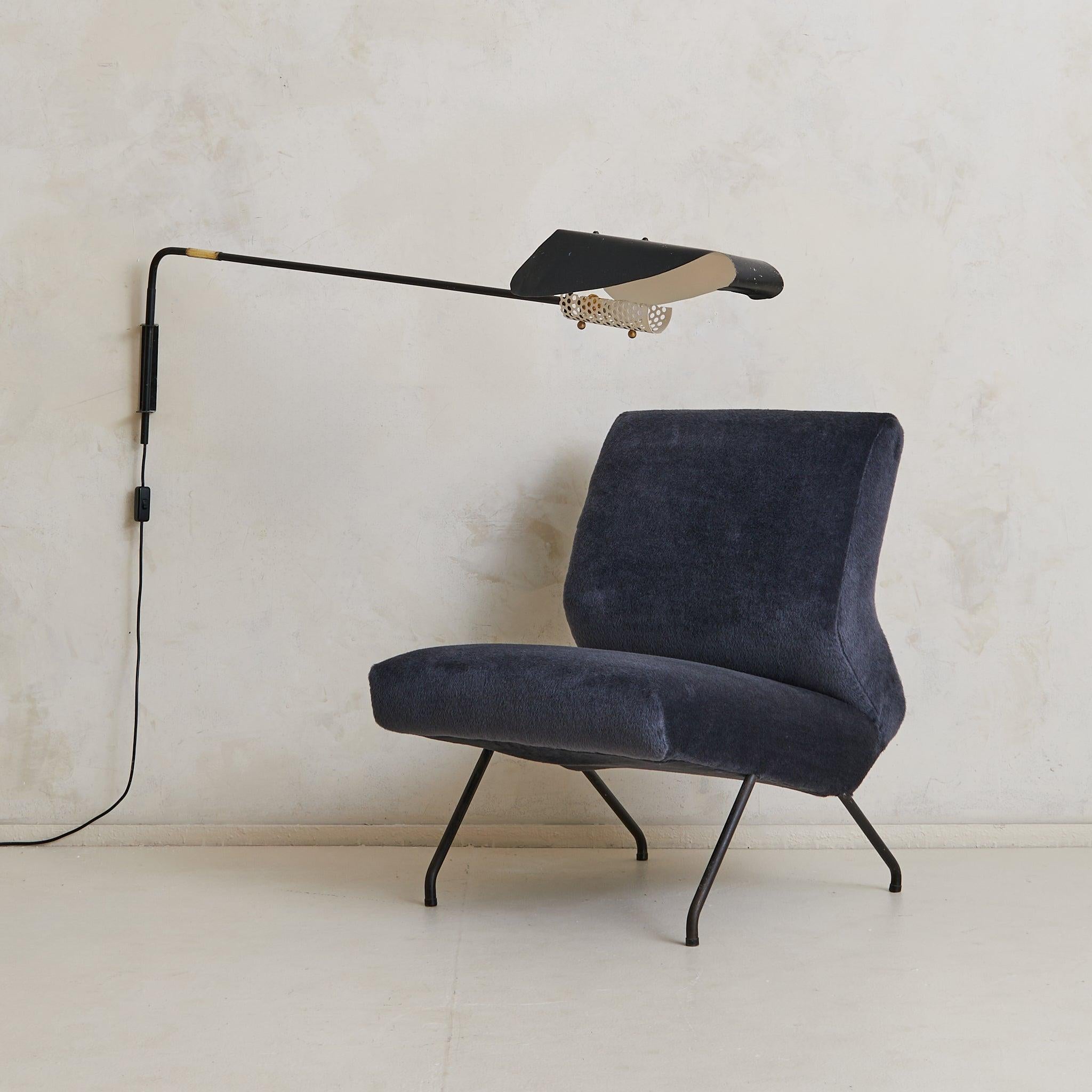A 1950s French lounge chair attributed to Geneviève Dangles and Christian Defrance. The sculptural frame is composed of black-lacquered tubular steel, splaying gently at the legs in a light-footed stance. The angular silhouette features a wide, low