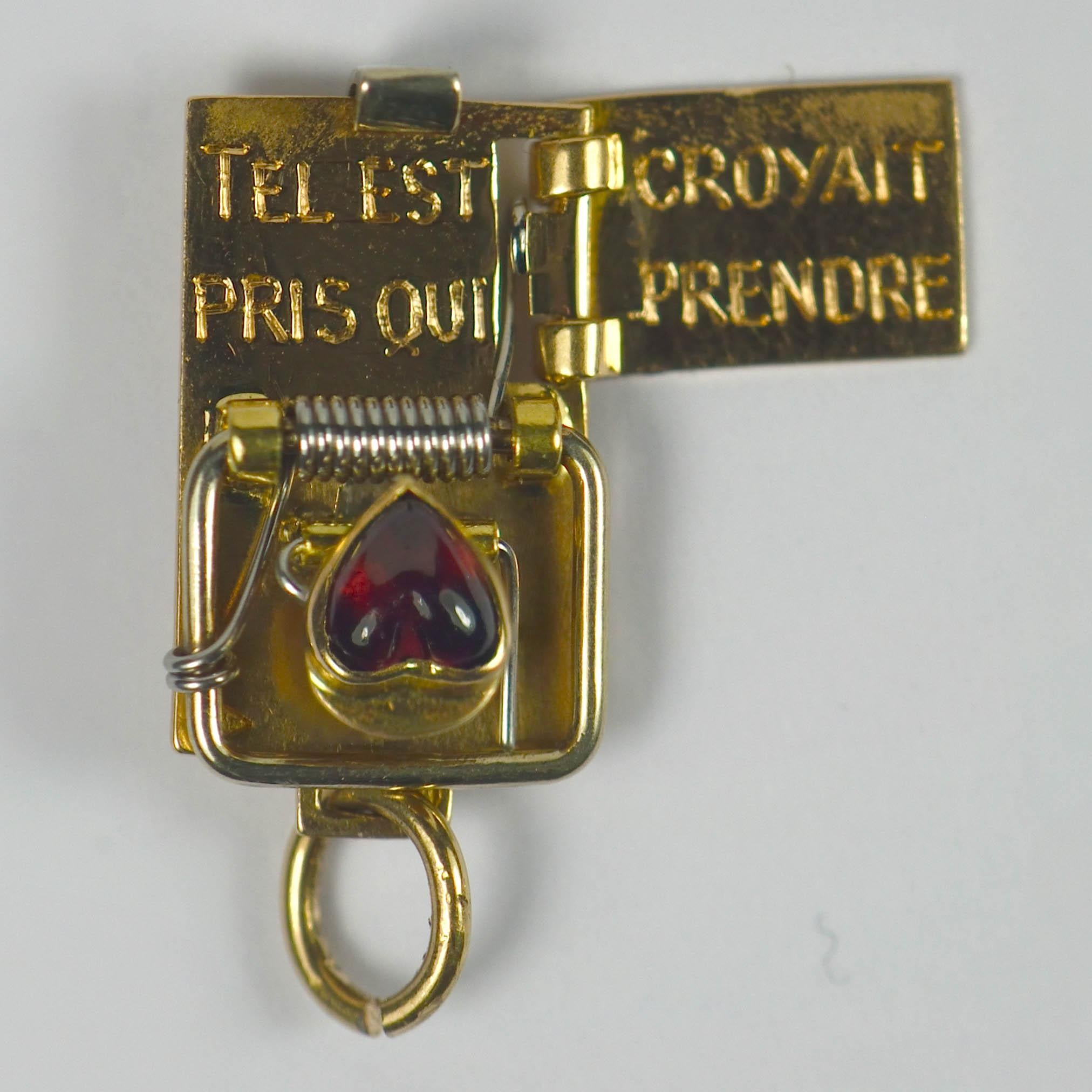 An rare and unusual French charm pendant designed as a garnet heart in a mouse trap, which opens with a slide mechanism to the reverse to reveal the words 