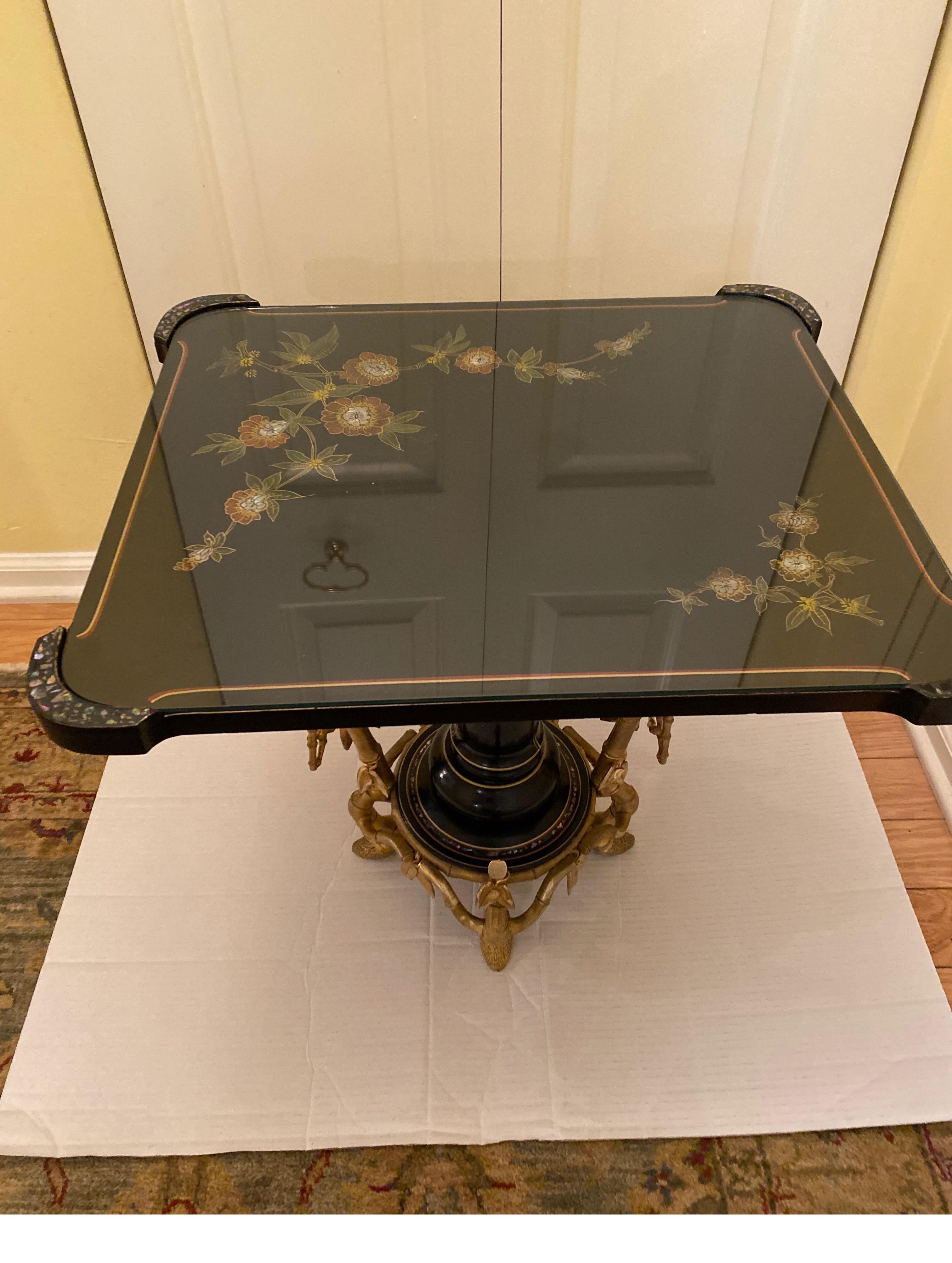 Une table de mouvement esthétique très chic de la célèbre maison de design Alphonse Giroux. Le plateau laqué noir peint à la main et la base en faux bronze doré. Le dessus est orné d'un motif floral avec incrustation de nacre. Un plateau en verre