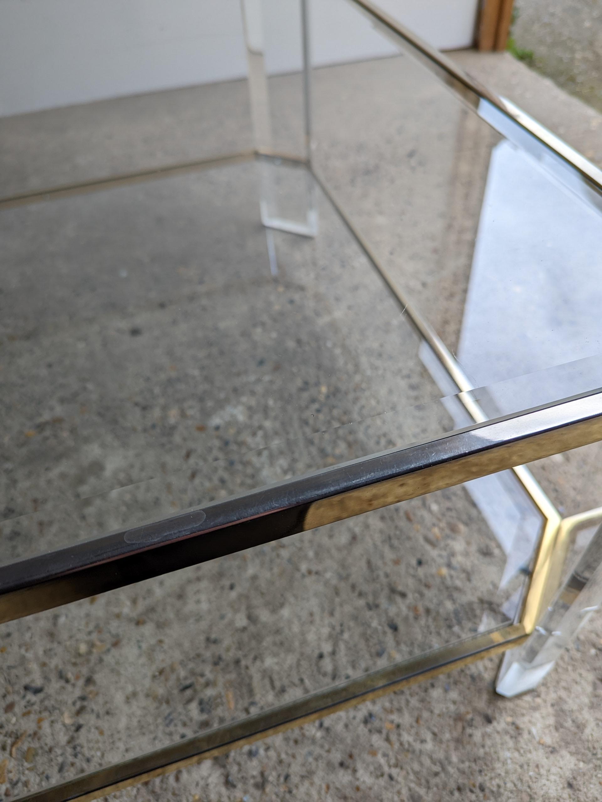 1970s French lucite coffee table featuring brass and glass shelving.