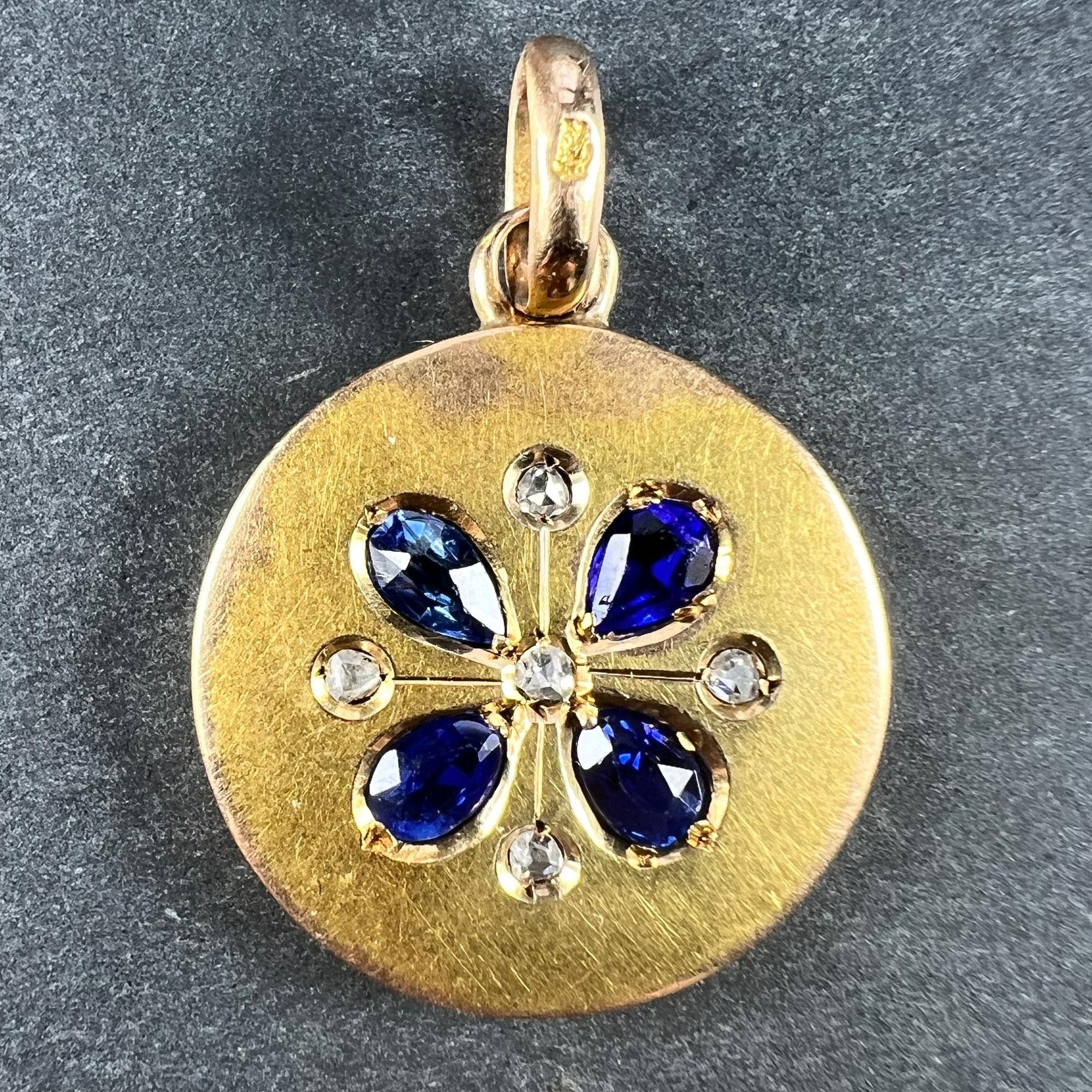 A French 18 karat (18K) yellow gold charm pendant designed as a lucky four-leaf clover or shamrock set with four pear-shaped blue sapphire and paste leaves, centring a rose-cut diamond, with rose-cut diamonds between each blue stone. One blue