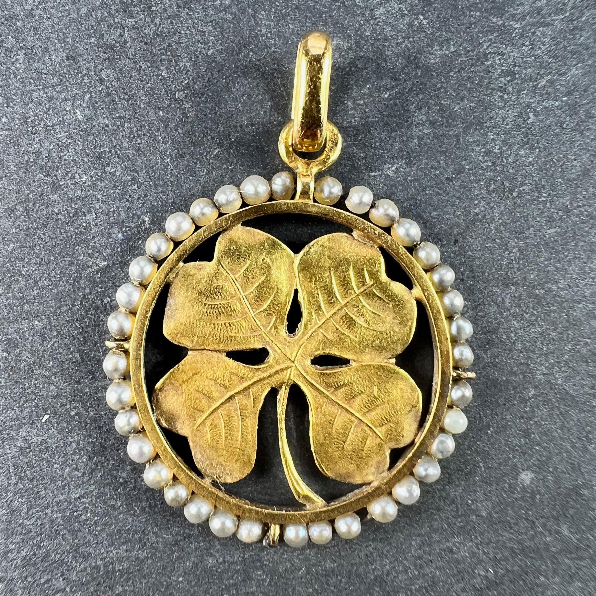 A French 18 karat (18K) yellow gold charm pendant designed as a four-leaf clover or lucky shamrock with finely detailed naturalistic leaves, within a circular frame outlined by 36 natural seed pearls. Stamped with the eagle’s head for French