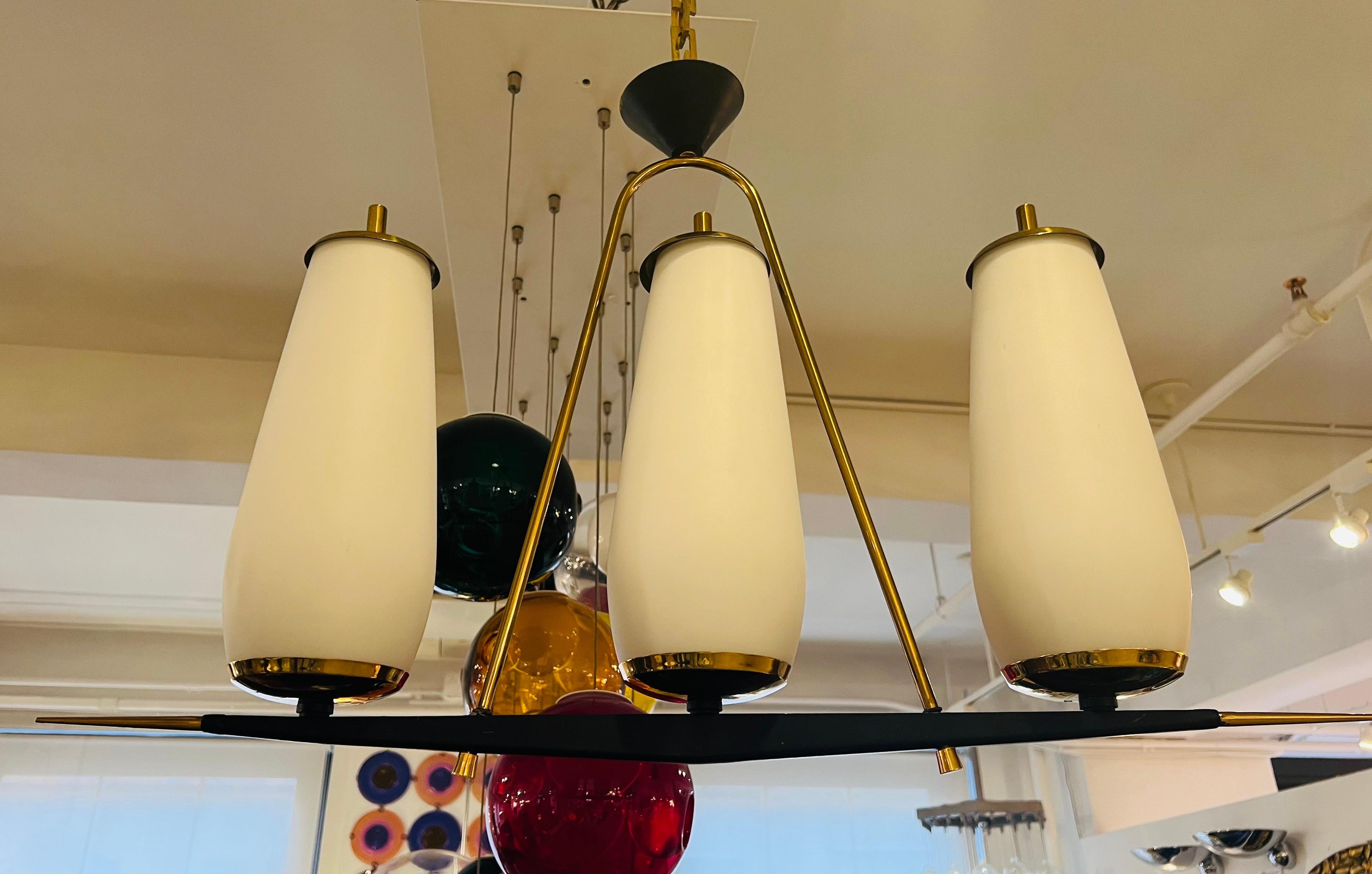 An original 1950s French pendant light in golden brass and matte black enamel with 3 large matte white glass shades. Made by the famed lighting company, Lunel. Rare with all original parts. Rewired. Three standard 150 watt sockets.