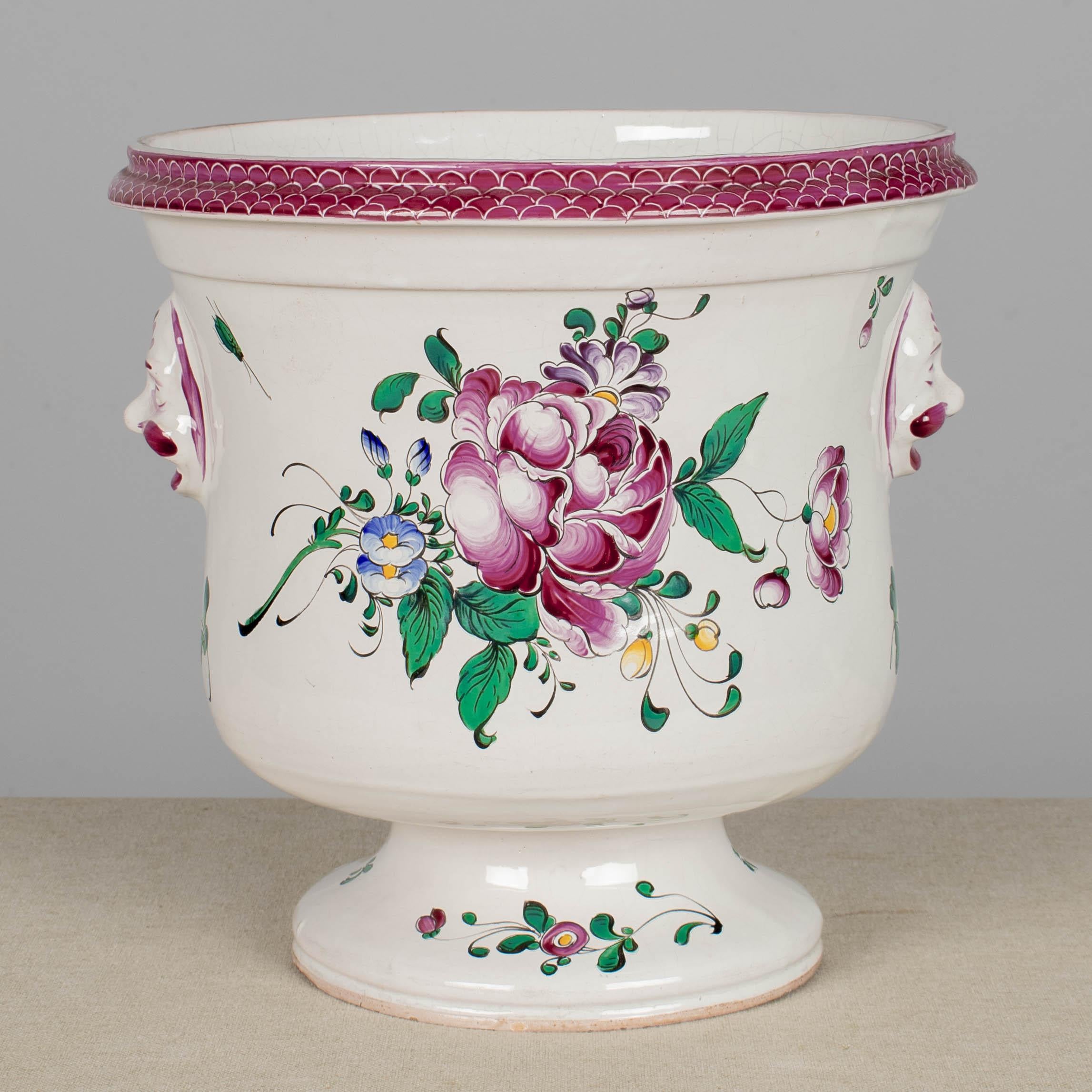 Cache-pot ou jardinière en faïence de Lunéville Saint Clément. Peint à la main dans un design floral typique avec des couleurs vives de rose, vert, violet, bleu et jaune sur fond blanc. Poignées latérales à face sculpturale en relief. Petites pertes