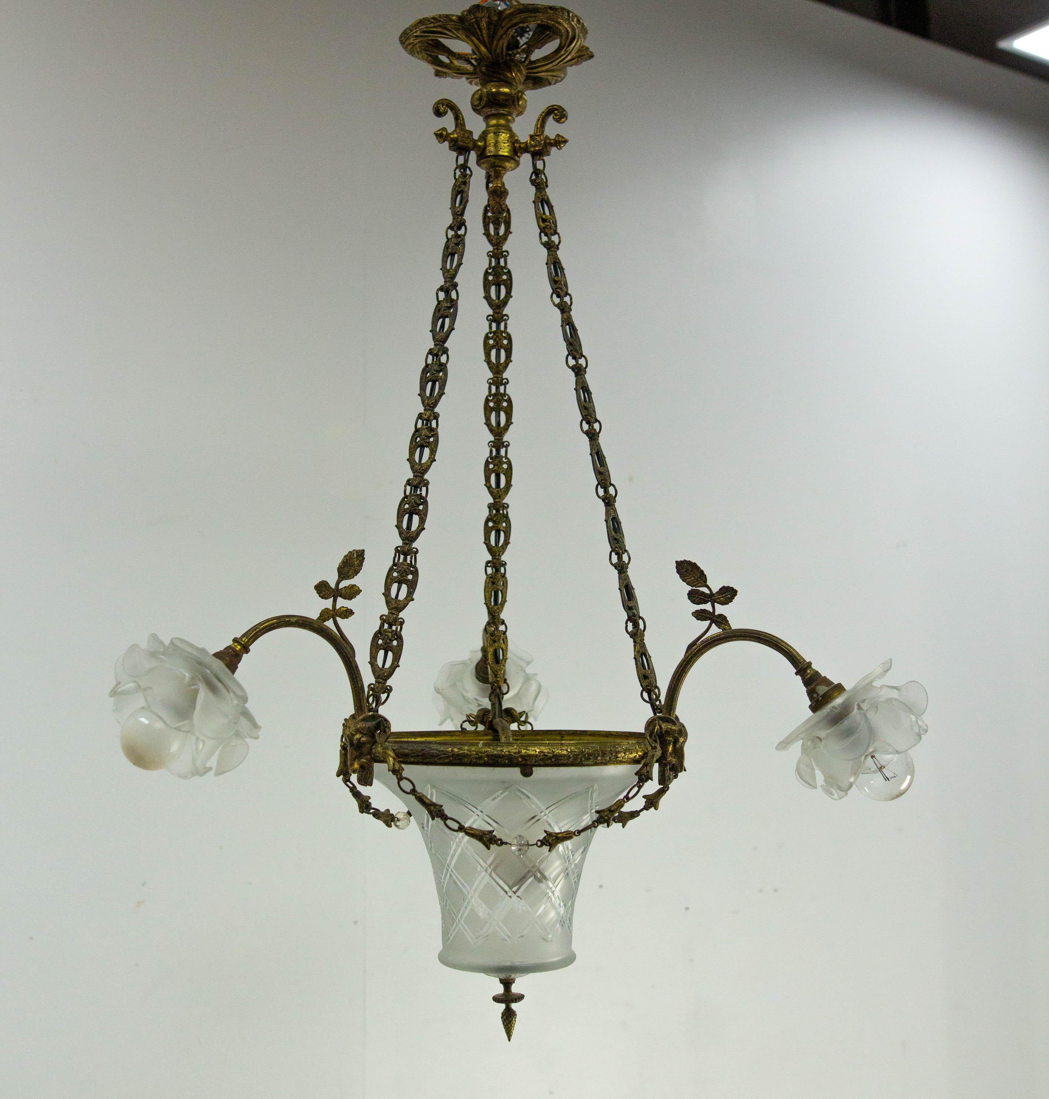 Romantic chandelier or lustre, French
Polished and engraved glass and brass.
Made circa 1910, this ceiling pendant takes up the theme of nature: carved flowers and leaves, as well as a goat's head, are depicted on the brass section.
These are