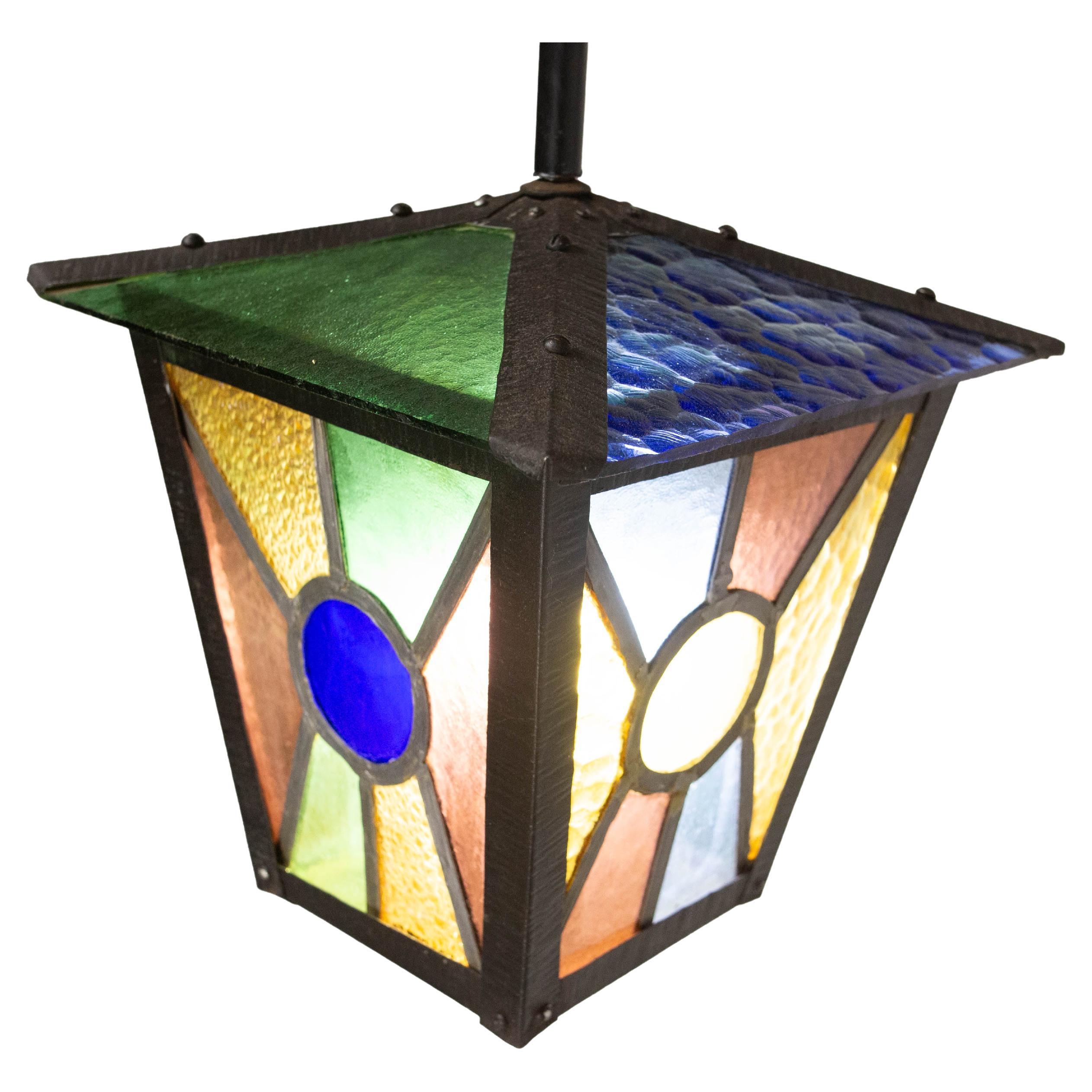 Mid century period chandelier or lustre, French
Wrought iron, colored blue, green, brown and yellow glass, textured glass 
Made in the late mid century
Good condition.
This item is suitable to USA or EU and UK standards.

Shipping:
55/25/25 cm 3.4 kg