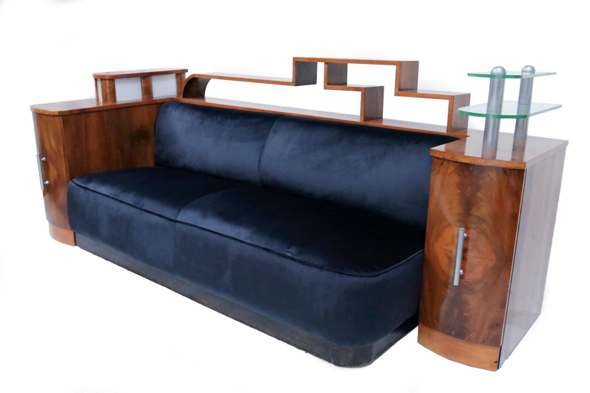 Extreme Luxury Glamorous French Art Deco Sofa / Cozy corner, circa 1925.
Rare is the integrated light on the left and the 2 glass shelves on the right. 
The sofa has new dark blue velvet fabric.
Extraordinary design!

 1 Total width 252 Max