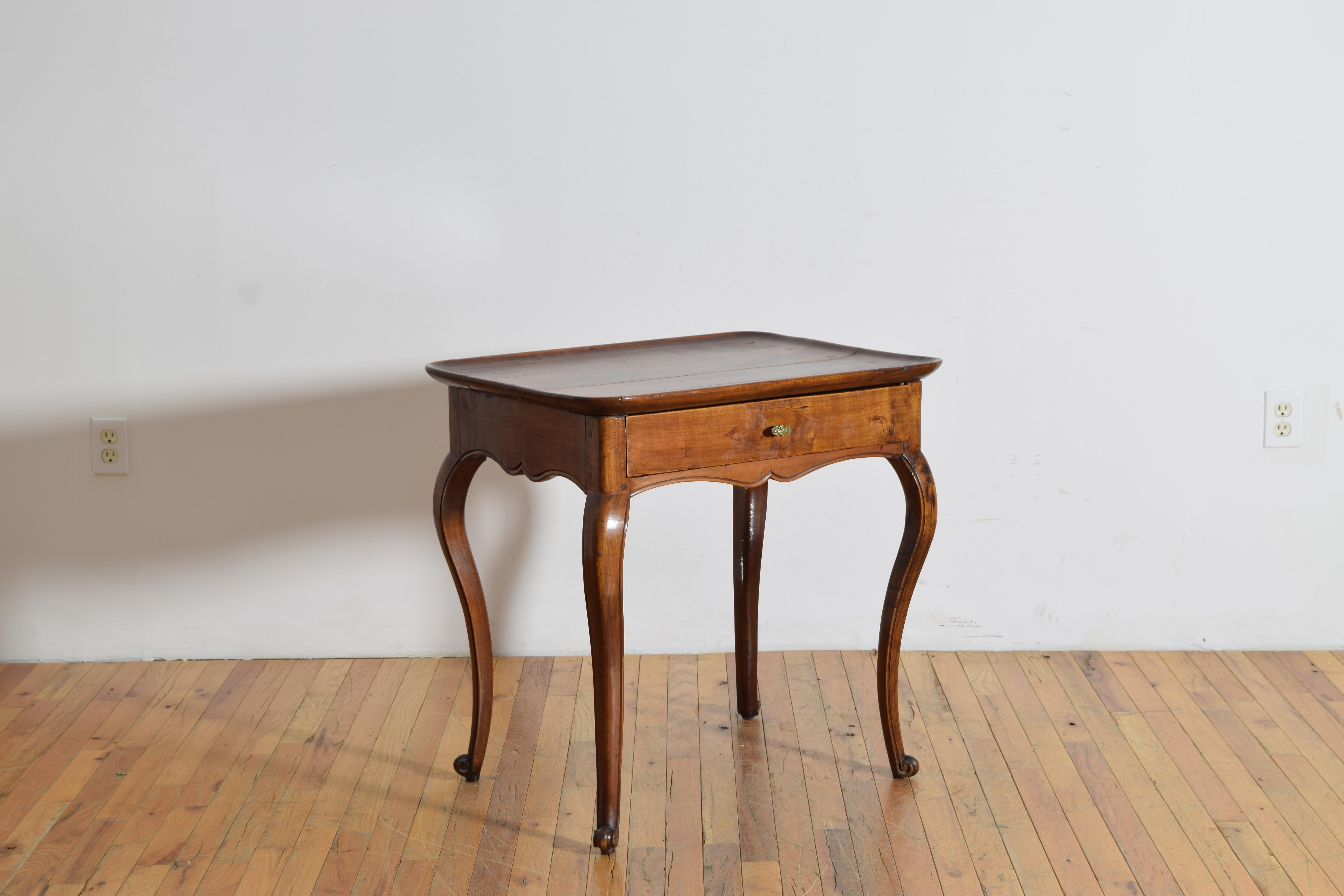 having a rectangular top with a curved gallery edge carved into it, the top above a conforming case housing one drawer and having a shaped and carved apron, raised on cabriole legs terminating in escargot feet