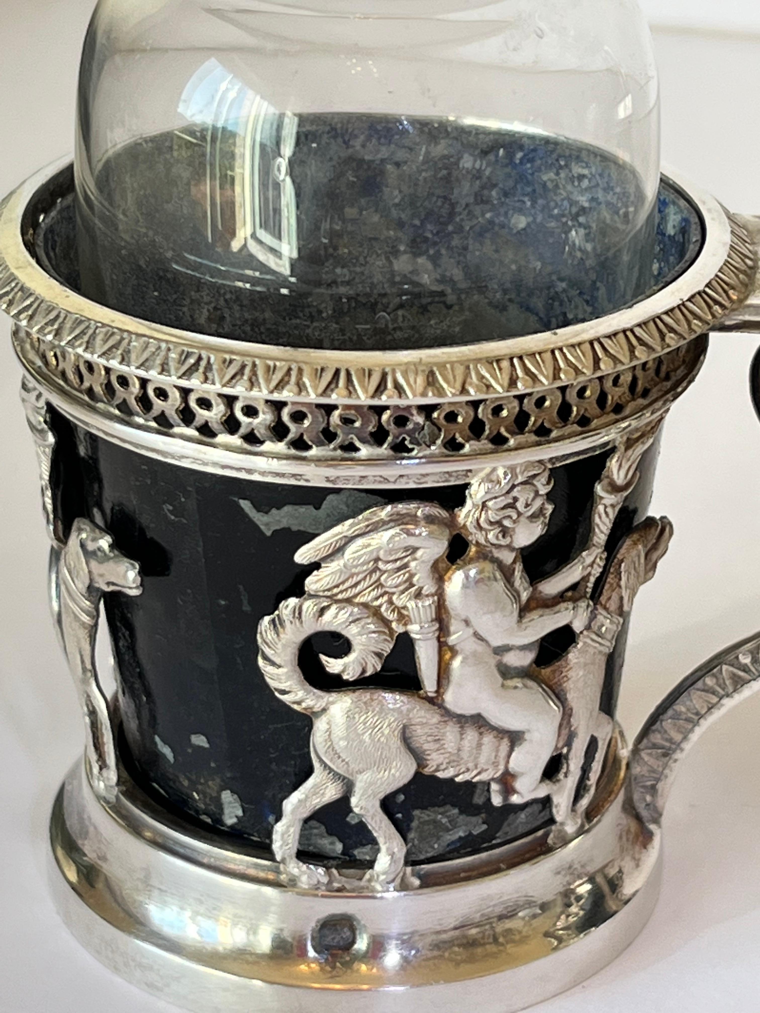 Squisito set di olio e aceto LXVI Argento e cristallo.
Animale dal design neo classico e figura alata di bambino cesellata in modo molto delicato.
La parte centrale con drappeggi intorno alla colonna che termina con due teste di cane.
Oggetto