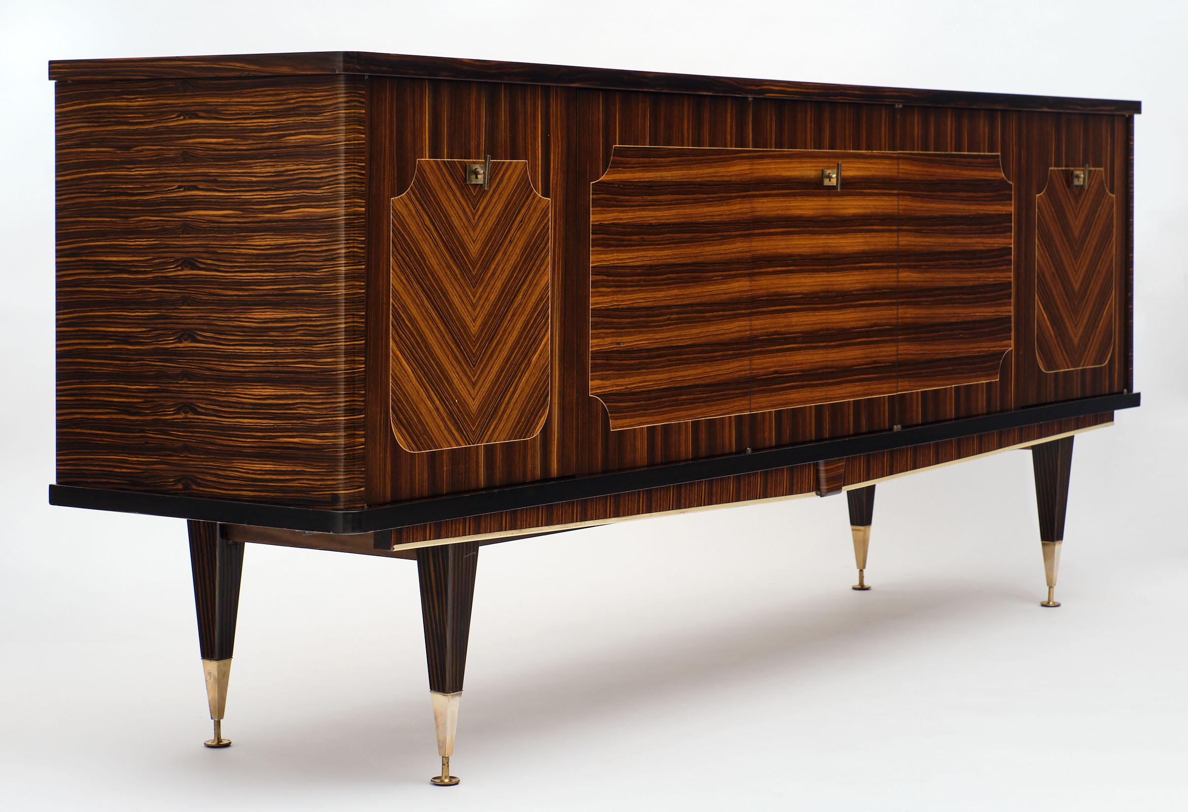 Macassar of ebony French vintage buffet with a very elegant parqueted inlay on the front doors. The doors open to a satin wood interior with a bar compartment and shelves. We love the finely crafted cabinet with four tapered legs finished with gilt