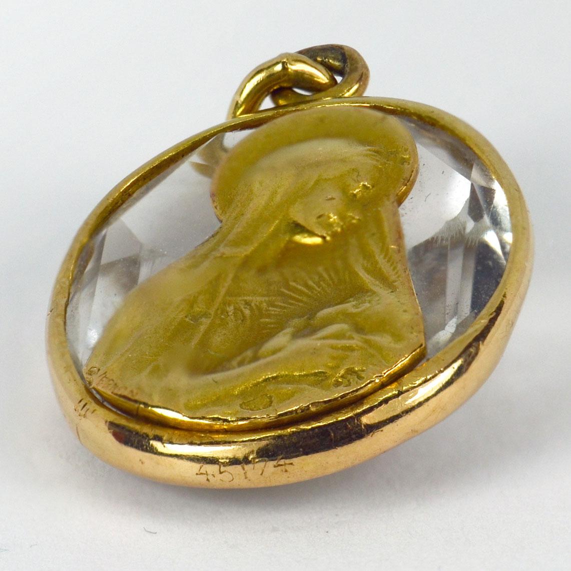 A French 18 karat (18K) yellow gold charm pendant designed as an oval faceted rock crystal in a gold frame, with an inset gold plaque depicting the Madonna and child. Signed G. Vernon and numbered 45174. Stamped with the eagle’s head for French