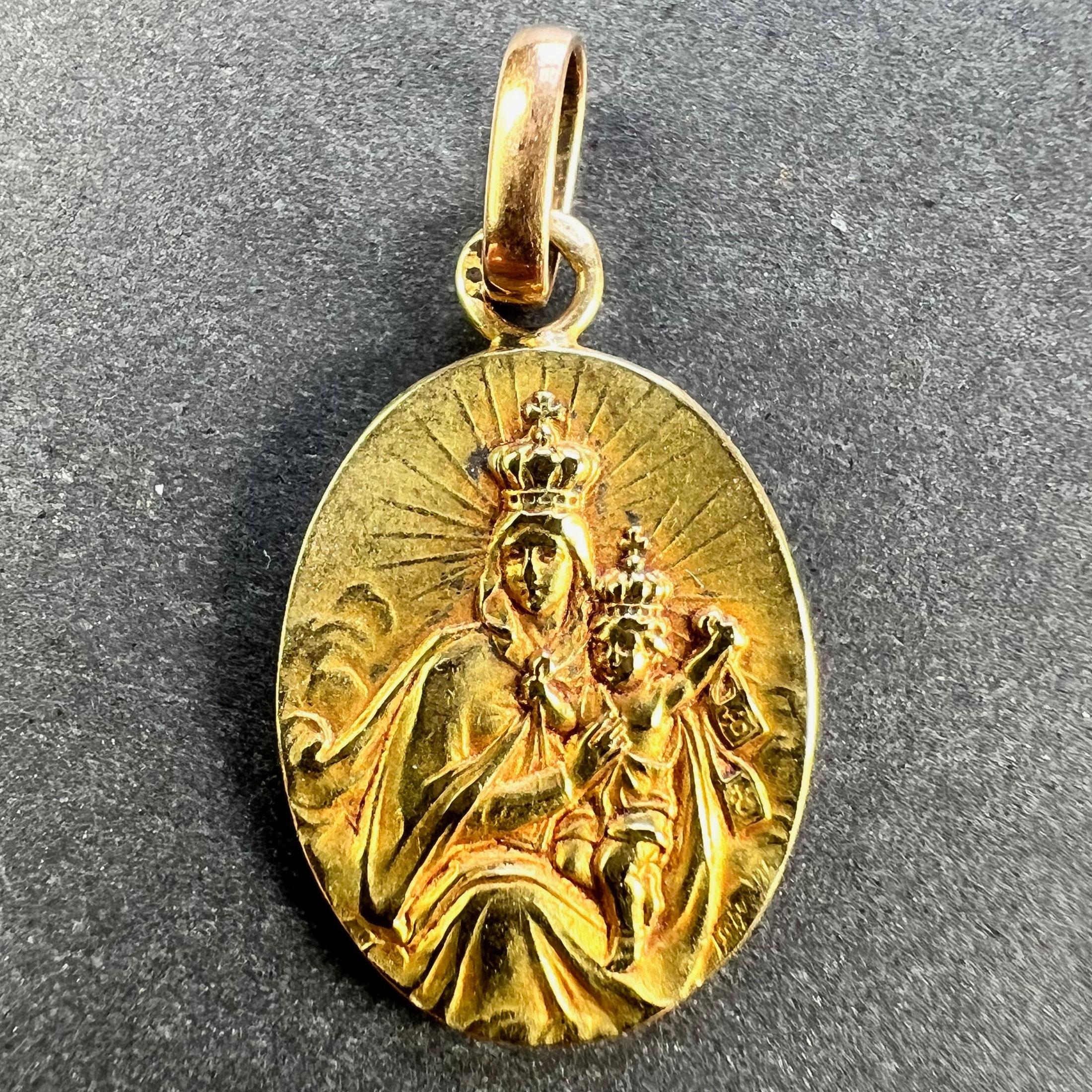 A French 18 karat (18K) yellow gold charm pendant designed as an oval medal depicting the Madonna and Child holding a pair of devotional scapulars to one side. The other side depicts Jesus Christ with the Sacred Heart. Stamped with the eagle's head