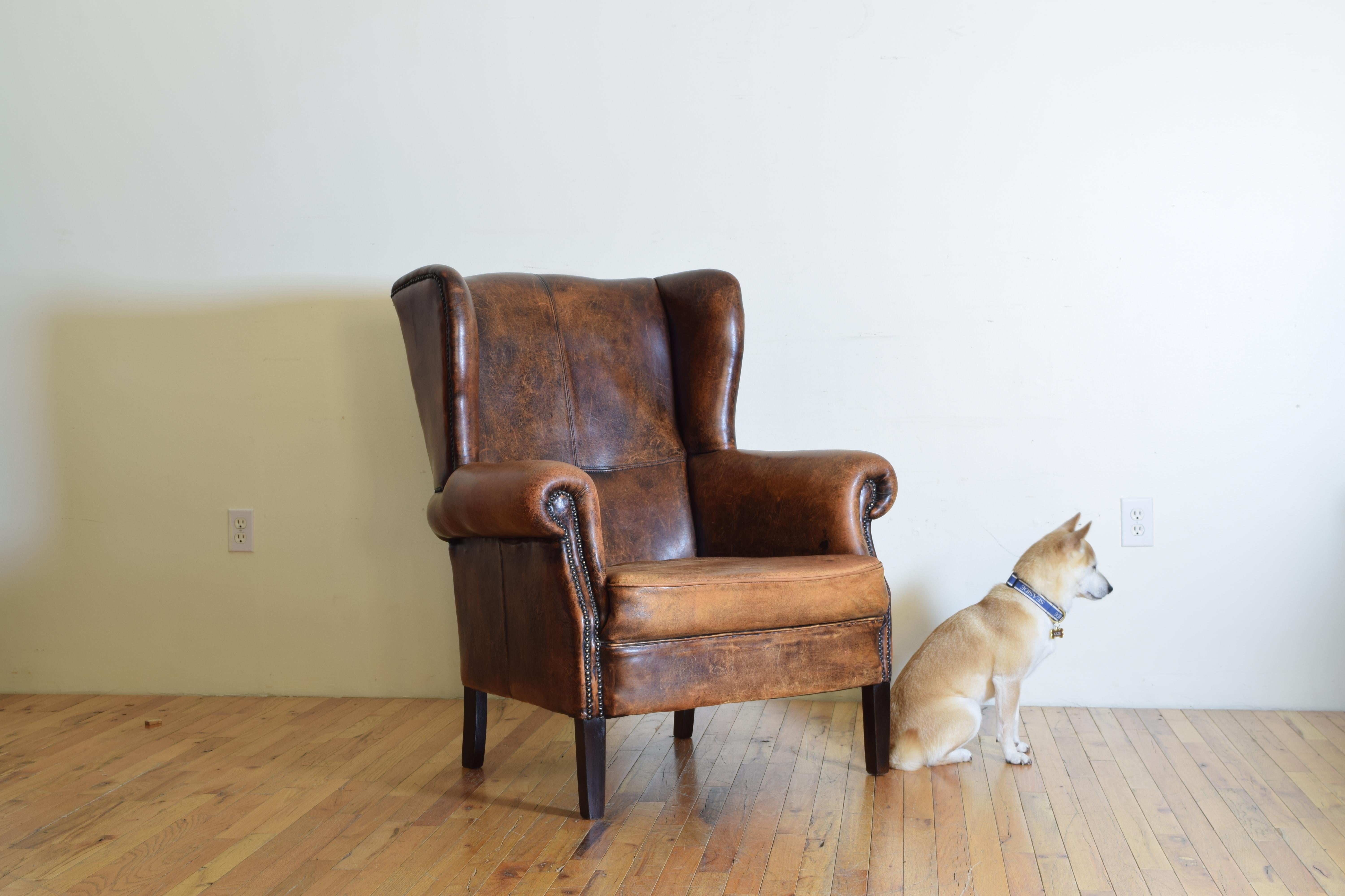 Having fitted seat, upholstered in sheepskin, trimmed in patinated brass nailheads, raised on tapering front legs, the rear legs slightly splayed, third quarter of the 20th century.
