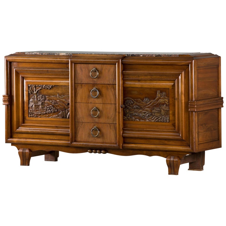 Spectacular and unusual Art Deco sideboard. Mahogany and Paysage sculpted doors. The base has a superb, very graphic line. The doors are elaborately carved in relief, representing an agricultural scene. The doors open onto two shelving areas