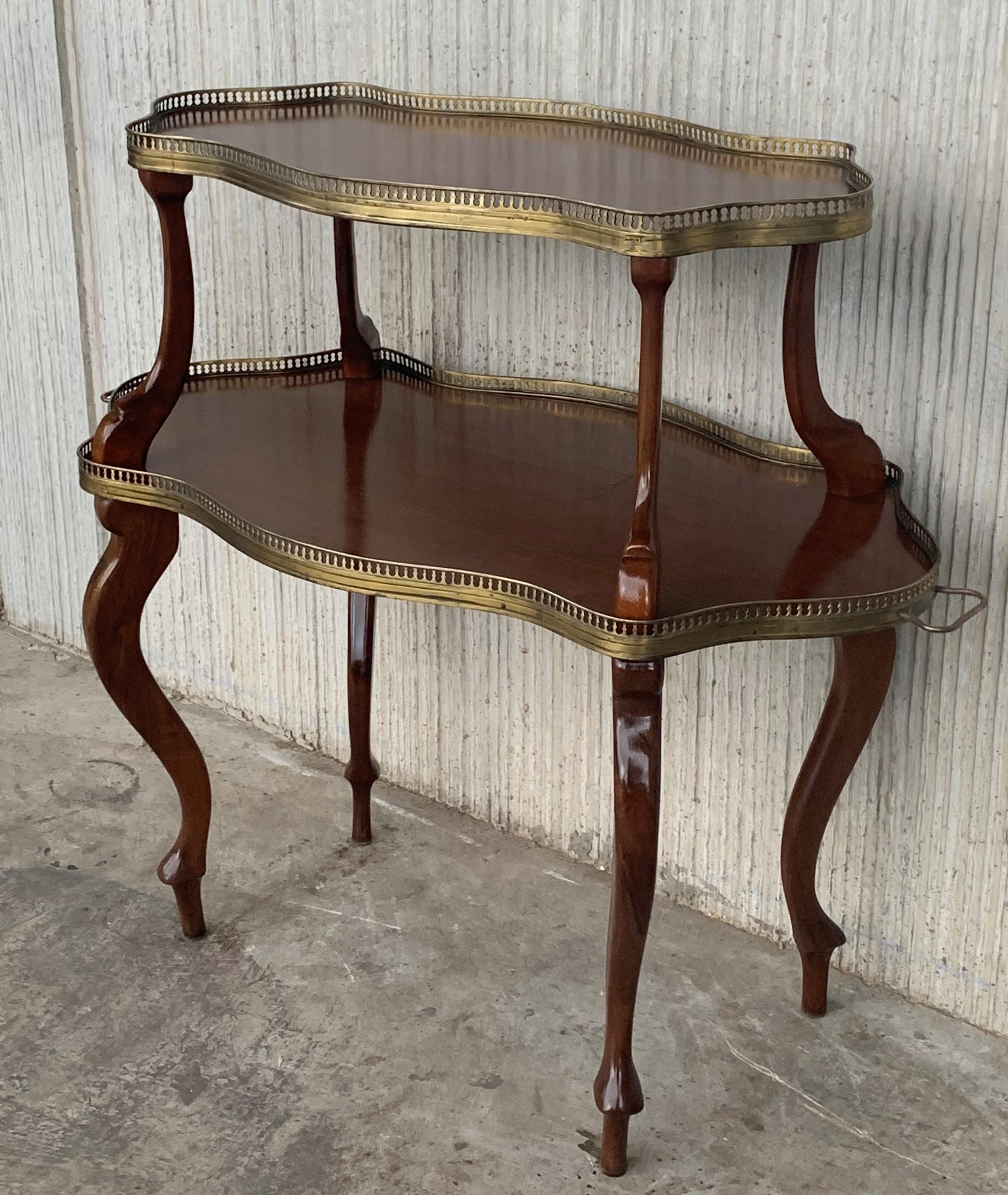 A charming French 19th century Louis XVI style side table in mahogany. The table is raised on cabriole legs. The table has two tiers decorated with pierced brass galleries. All below a bouillotte tole shade and two bronze handles in both