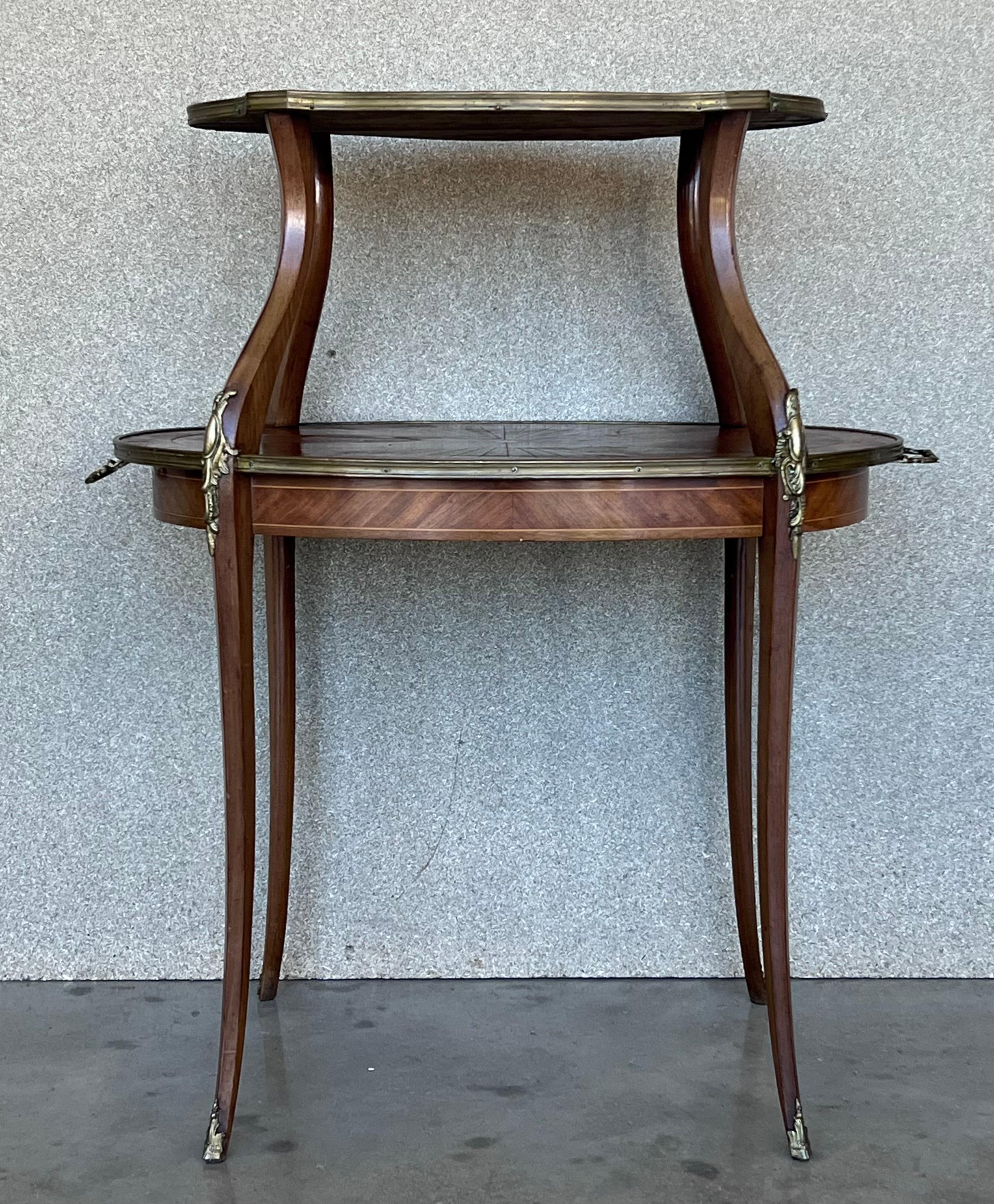 A charming French 19th century Louis XVI style side table in mahogany. The table is raised on cabriole legs. The table has two tiers decorated with pierced brass galleries. All below a bouillotte tole shade and two bronze handles in both