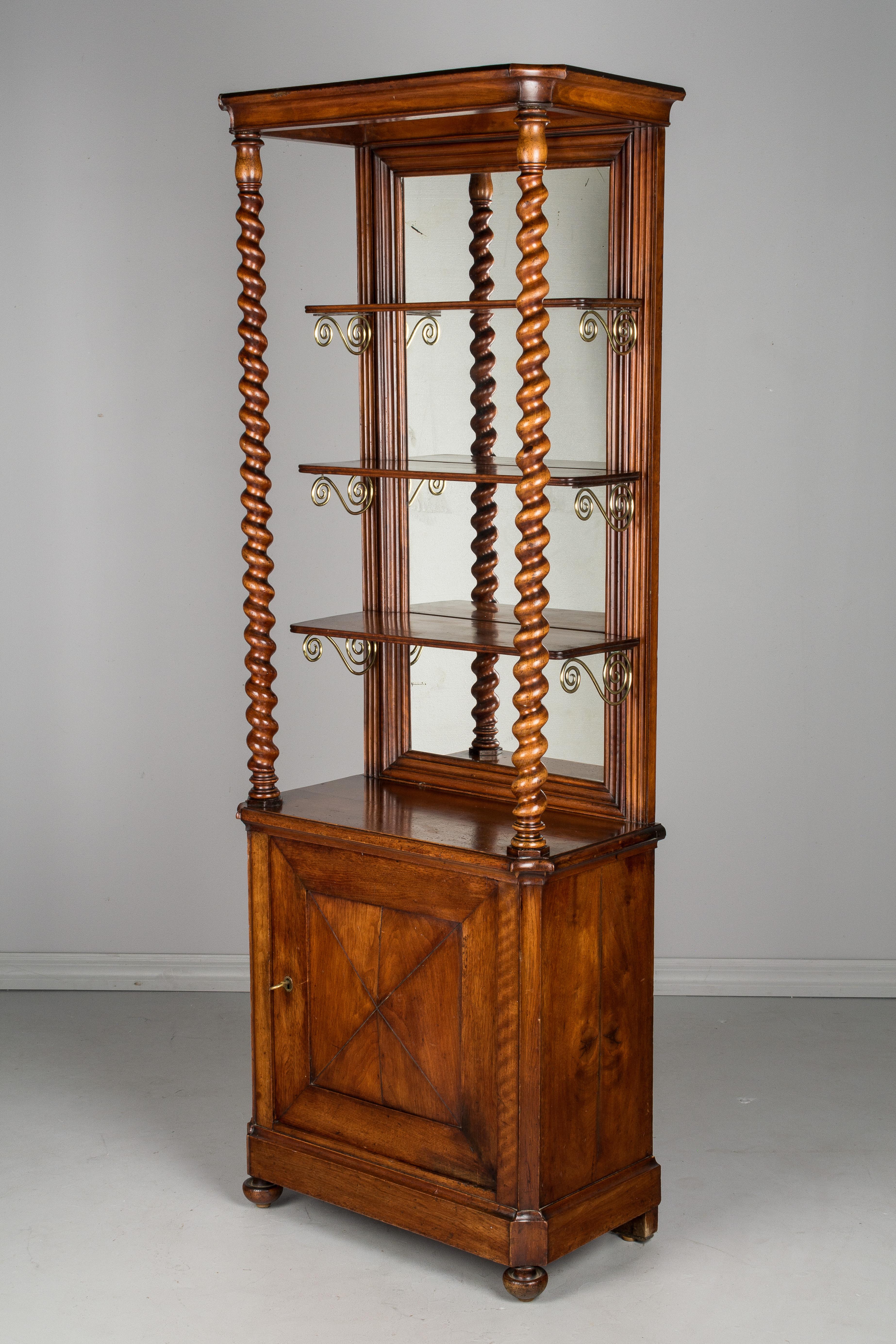 A 19th century French display cabinet from a chocolate shop. Made of solid mahogany with barley twist columns, a mirrored back and three shelves with brass supports. Cabinet with working lock and key opens to one shelf. The mirror is old with nice