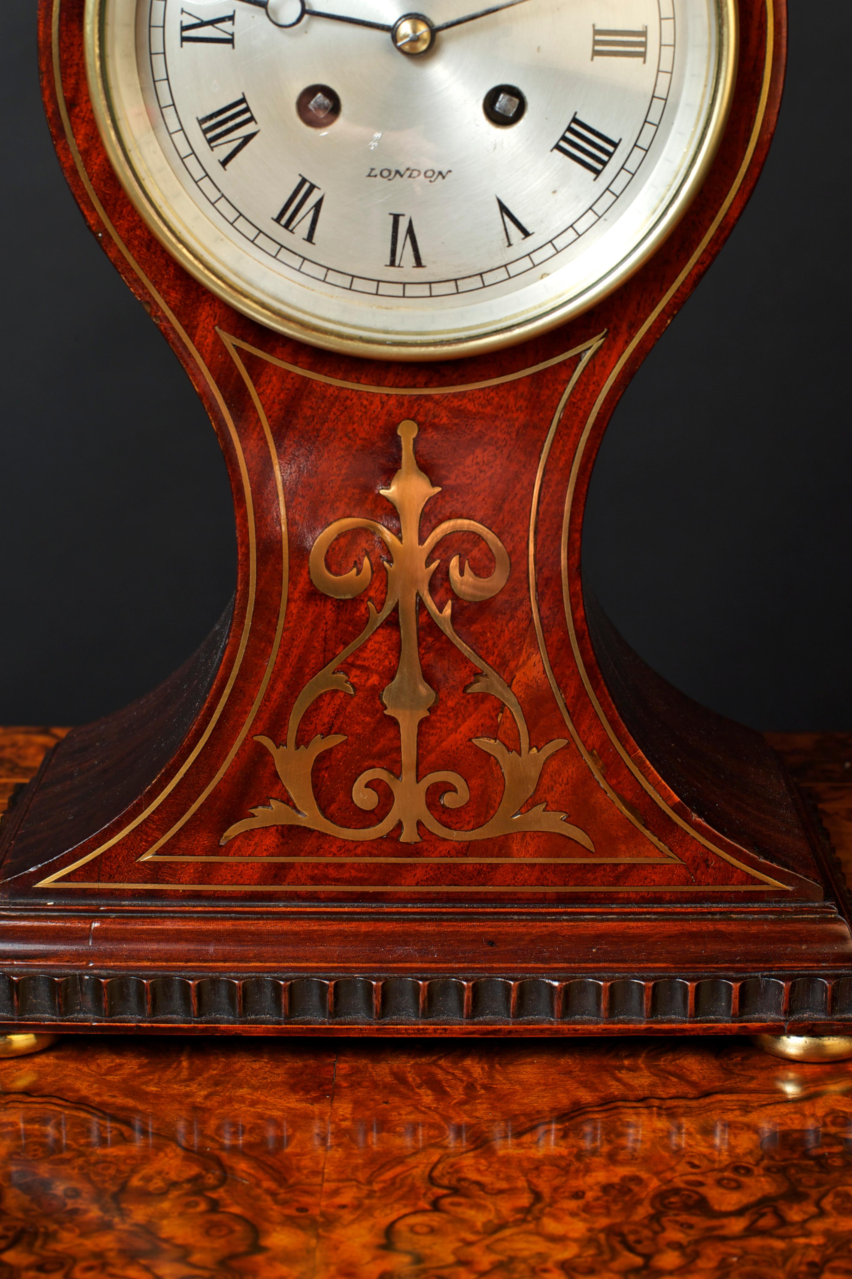French mahogany balloon clock standing on brass bun feet with dentil moulding and brass inlay. Silvered dial with Roman numerals signed W.Barfoot, London. 

Eight day French movement striking the hours and halves on a coiled gong, circa