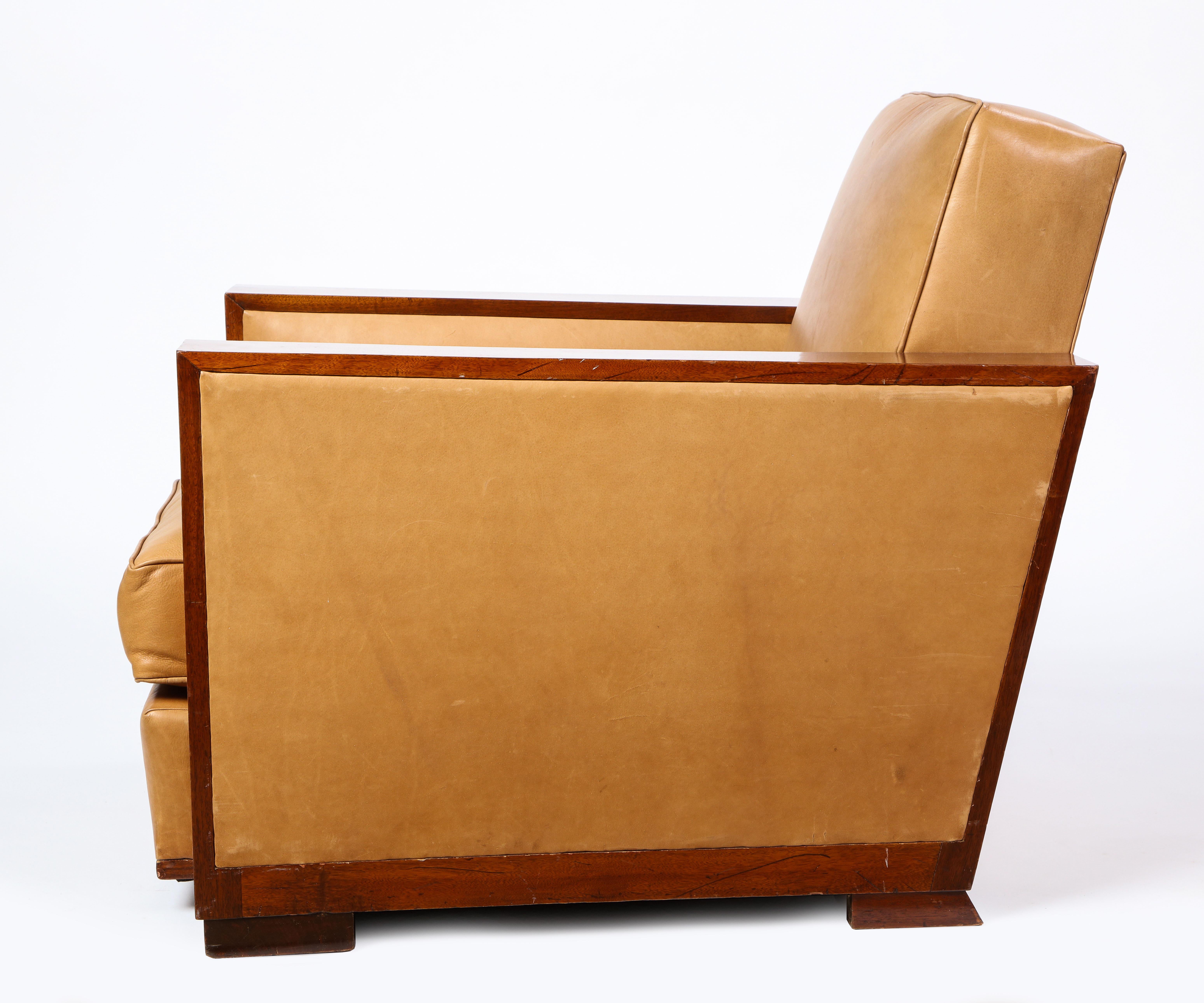 This French mid-20th century leather upholstered and mahogany club chair is attributed to Dominique. Upholstered with a soft and comfortable buttery tan leather over warm mahogany. Its Art Deco style design is practical and chic and would be a