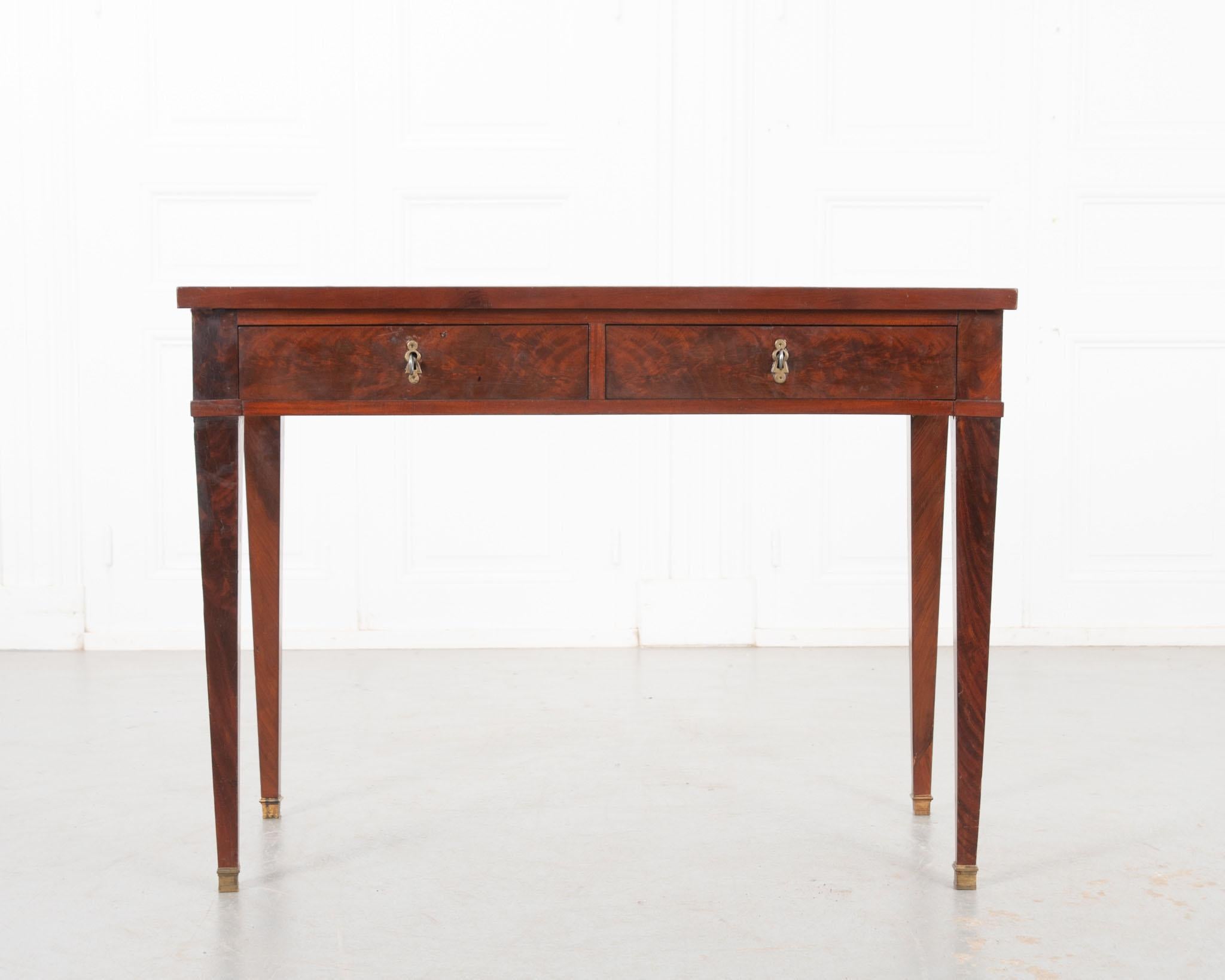 A handsome Directoire style writing desk crafted in France, circa 1820. Well worn hazelnut toned shagreen creates a cozy, welcoming place to work. A wonderful patina envelopes the distinctive mahogany veneer body. The apron houses two drink slides