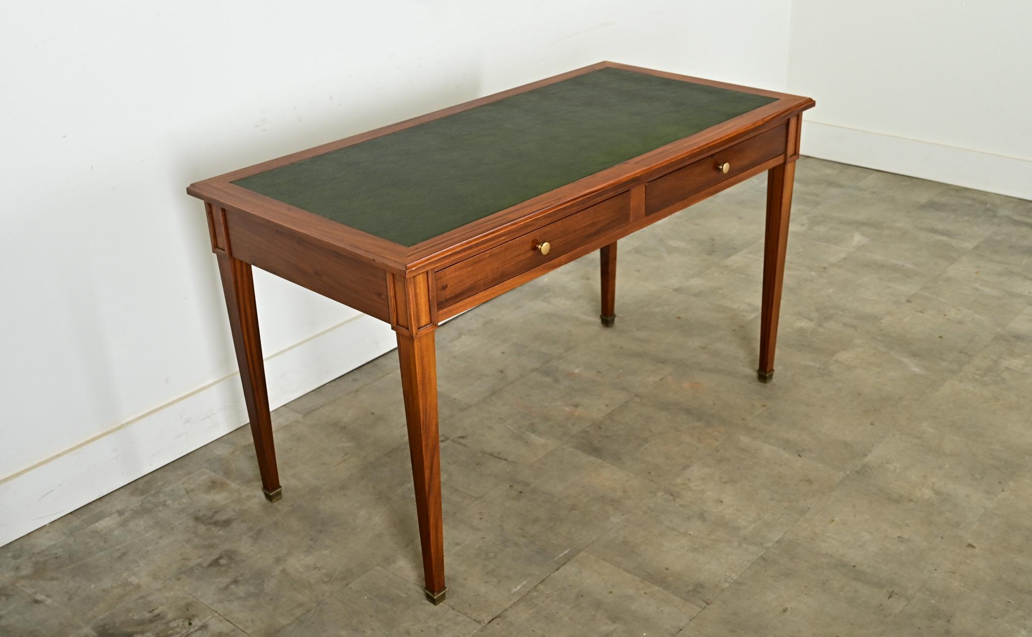 A classic writing desk from France based on the Louis XVI style, this is an early 20th century reproduction in mahogany with a dark green leather top. This piece is made of solid wood construction, finished with a lustrous polish to bring out the