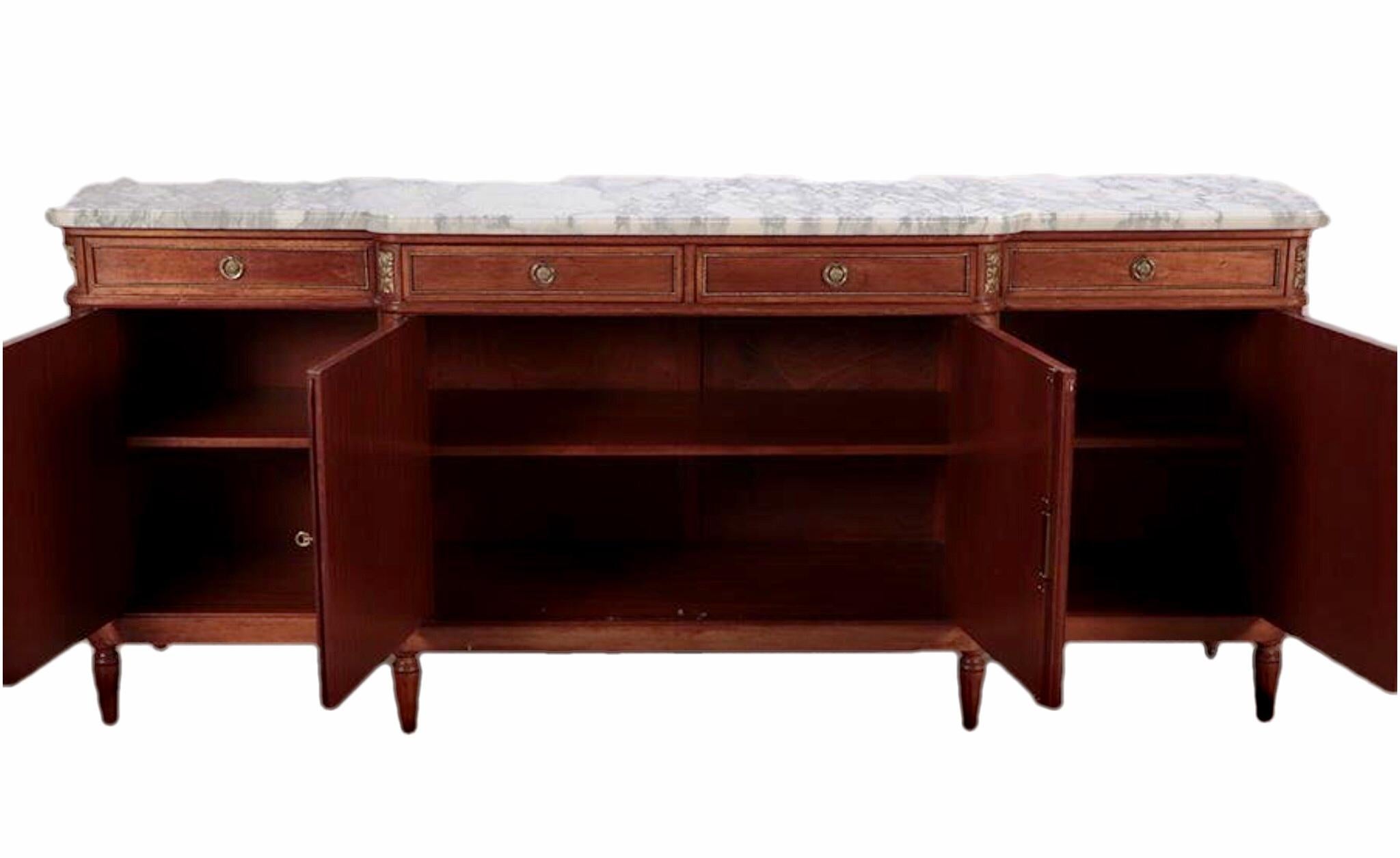 Very impressive Louis XVI style mahogany enfilade, having white Carrara marble top over four drawers and cabinets leading to interior shelf storage, featuring bronze rosette hardware and trim, rising on tapered legs ending in brass sabots. A truly