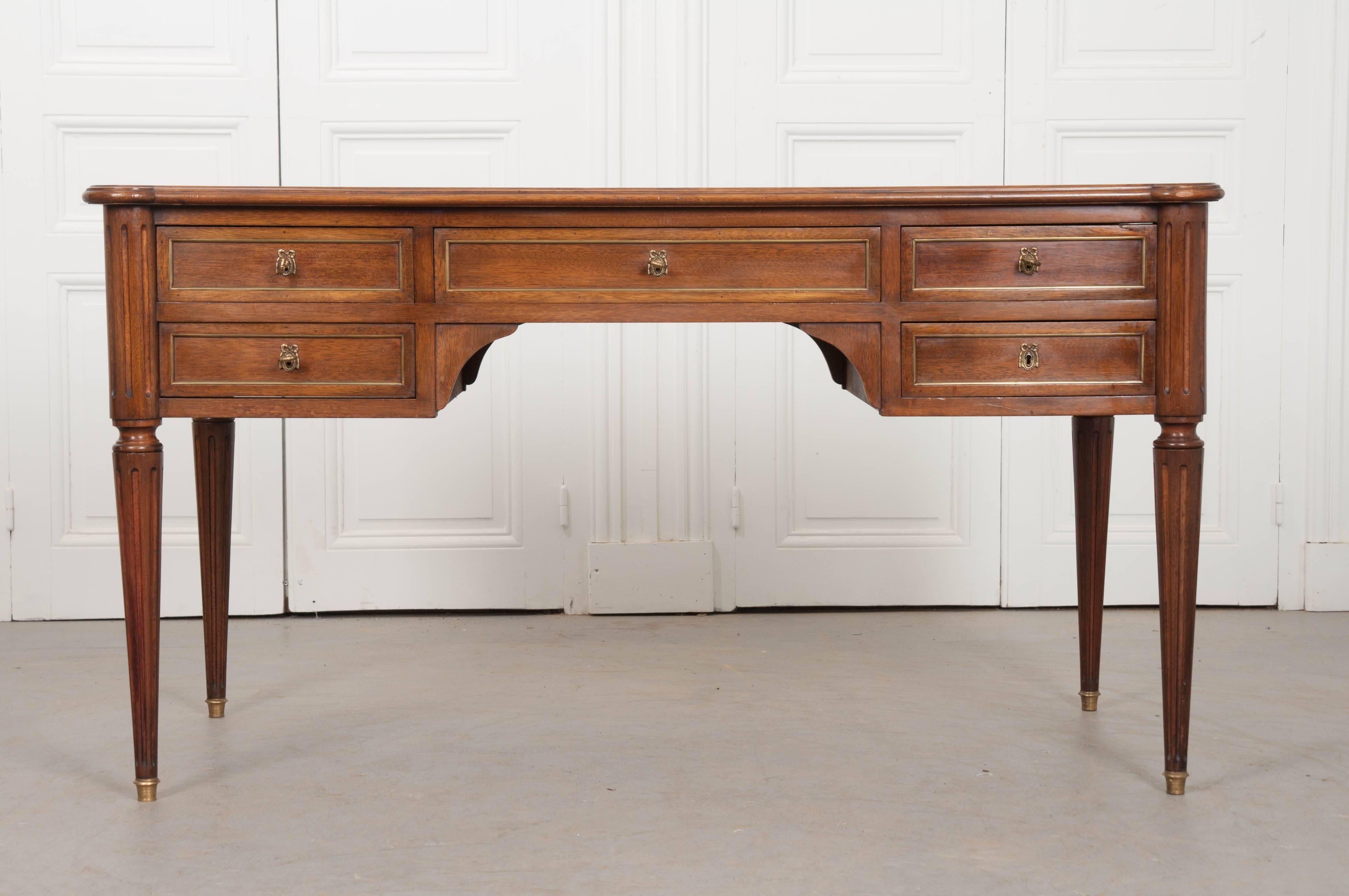 A sharp French Louis XVI style desk, made of mahogany, circa 1930, with a beautifully patinated leather top. This handsome desk is topped in a cognac colored leather, which is embellished with scrolled gold tooling. The desk has turreted corners