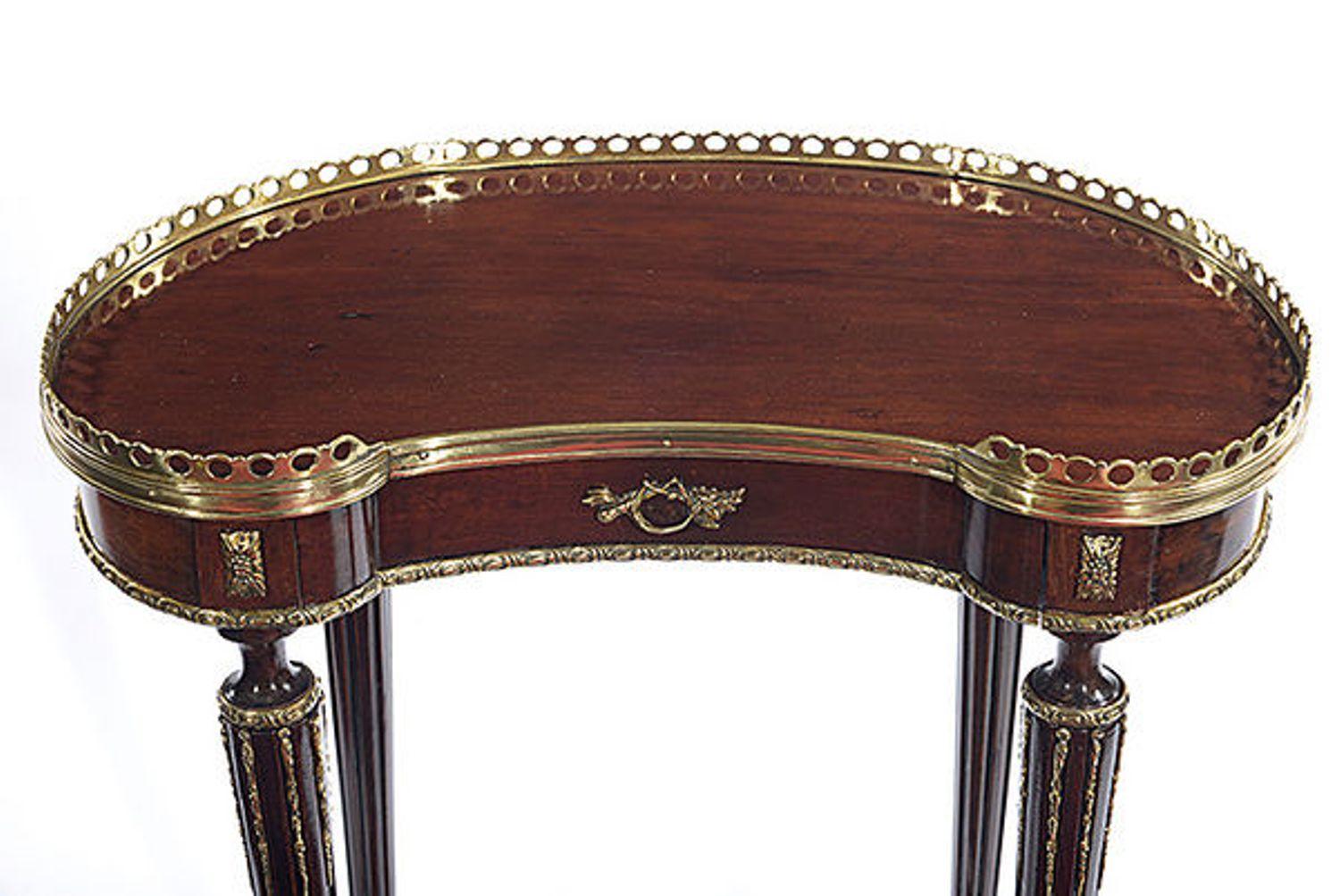 A Continental mahogany and metal mounted occasional table.
The kidney shaped top with a brass gallery and a fitted drawer with a brass handle.
The whole raised on four round tapered and fluted legs that unite with the stretcher below.