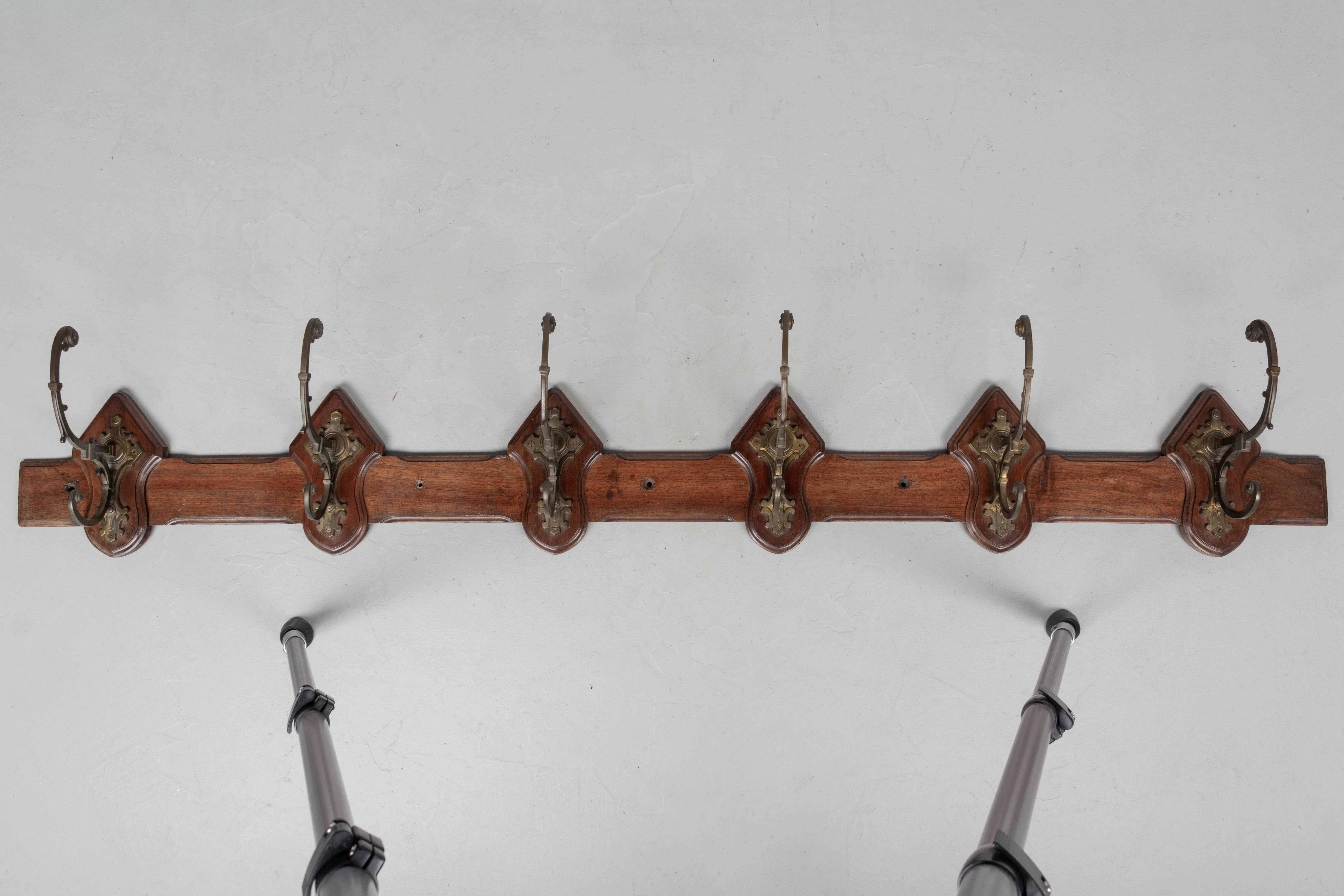 An early 20th century French mahogany wall mounted porte manteau, or coat rack, with six cast brass hooks. Good quality detailed casting. Circa 1900-1920. 
Dimensions: 71