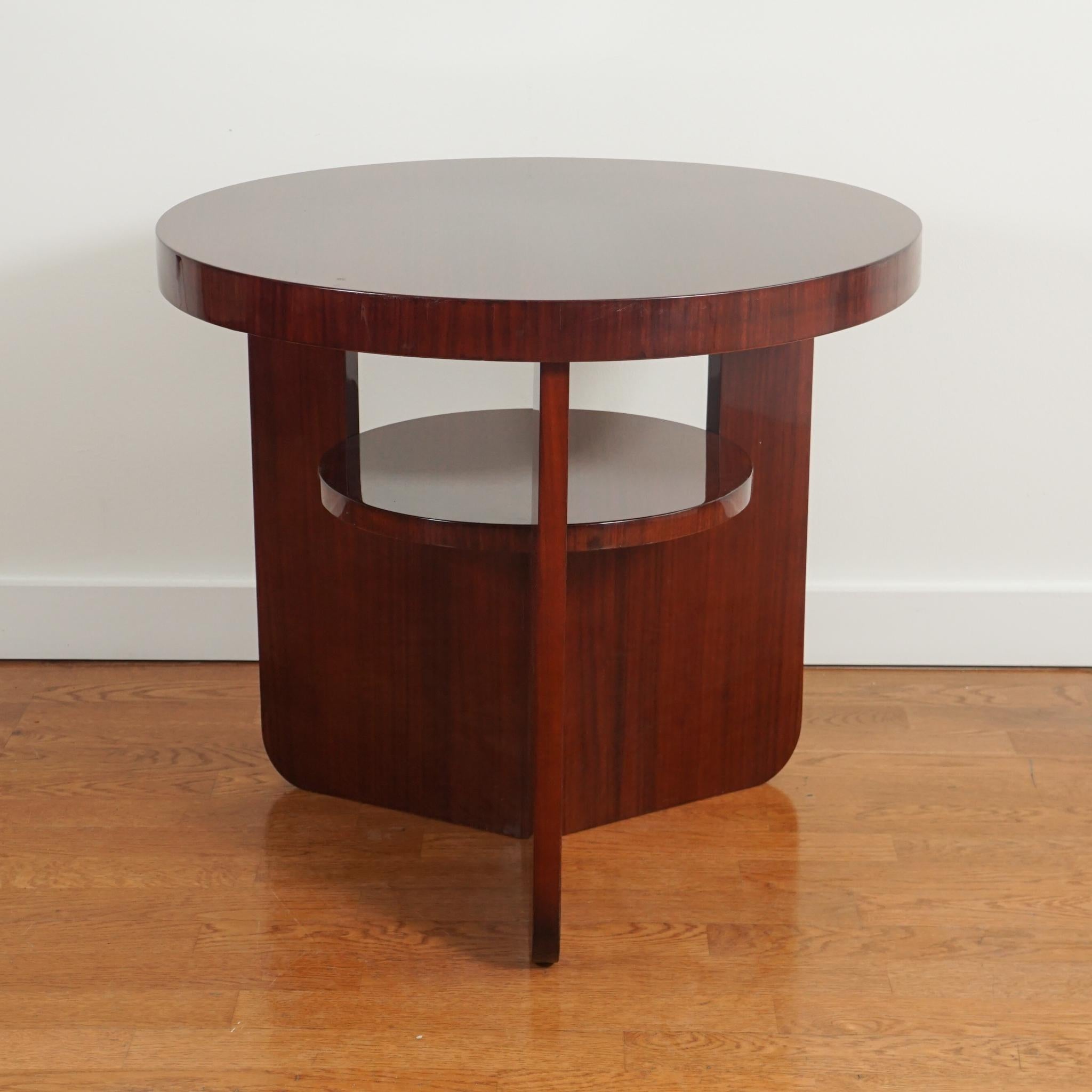 The French mahogany round side table, shown here, is from the 1930s.  Featuring an interesting triangular base with round middle shelf, the table is made even more distinctive by its rich, wood finish.  The table is in very good original condition.  
