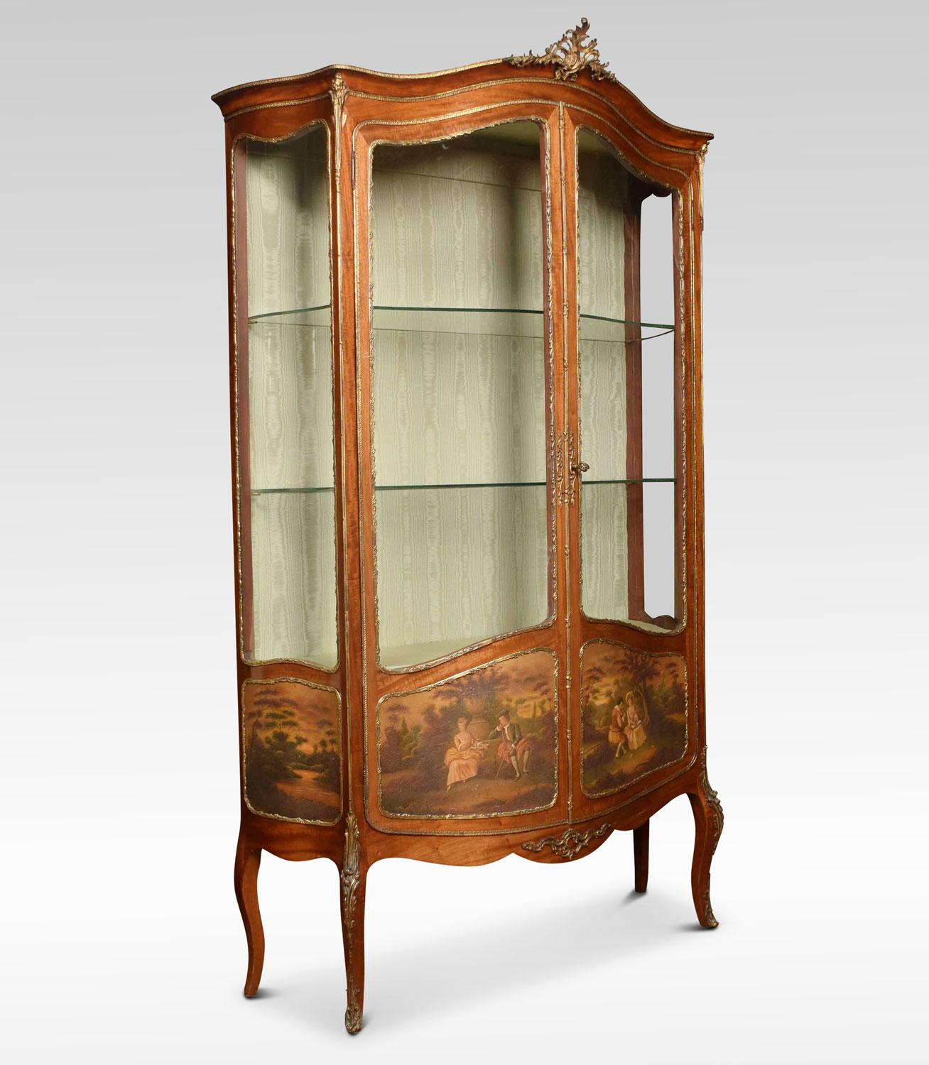French mahogany, gilt metal Vernis Martin vitrine. The flared serpentine top with pierced Rococo motif. Over a pair of serpentine glazed doors and sides, enclosing upholstered silk interior with two glass shelves. The lower doors and sides with