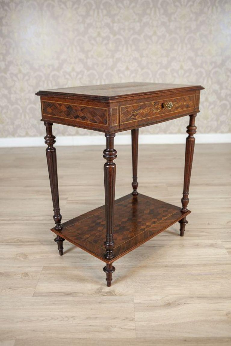 French Louis XVI Mahogany & Walnut Marquetry Side Table From the Early 20th Century

A French marquetry table in the Louis XVI style. The table, richly inlaid and featuring a small drawer, is made of mahogany and walnut on the outside. It has fluted