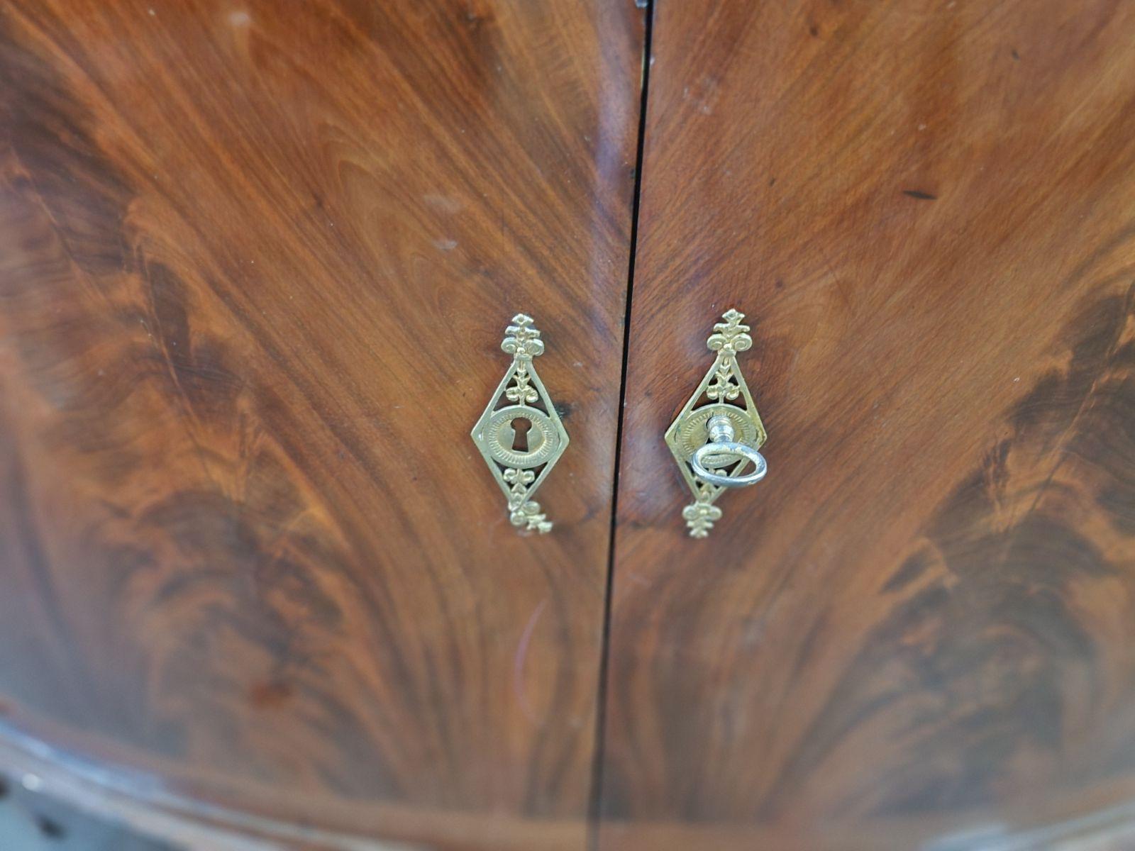 French Crotch Mahogany sideboard in a demi-lune shape. With a gray marble top and bronze mounts. With four doors. 