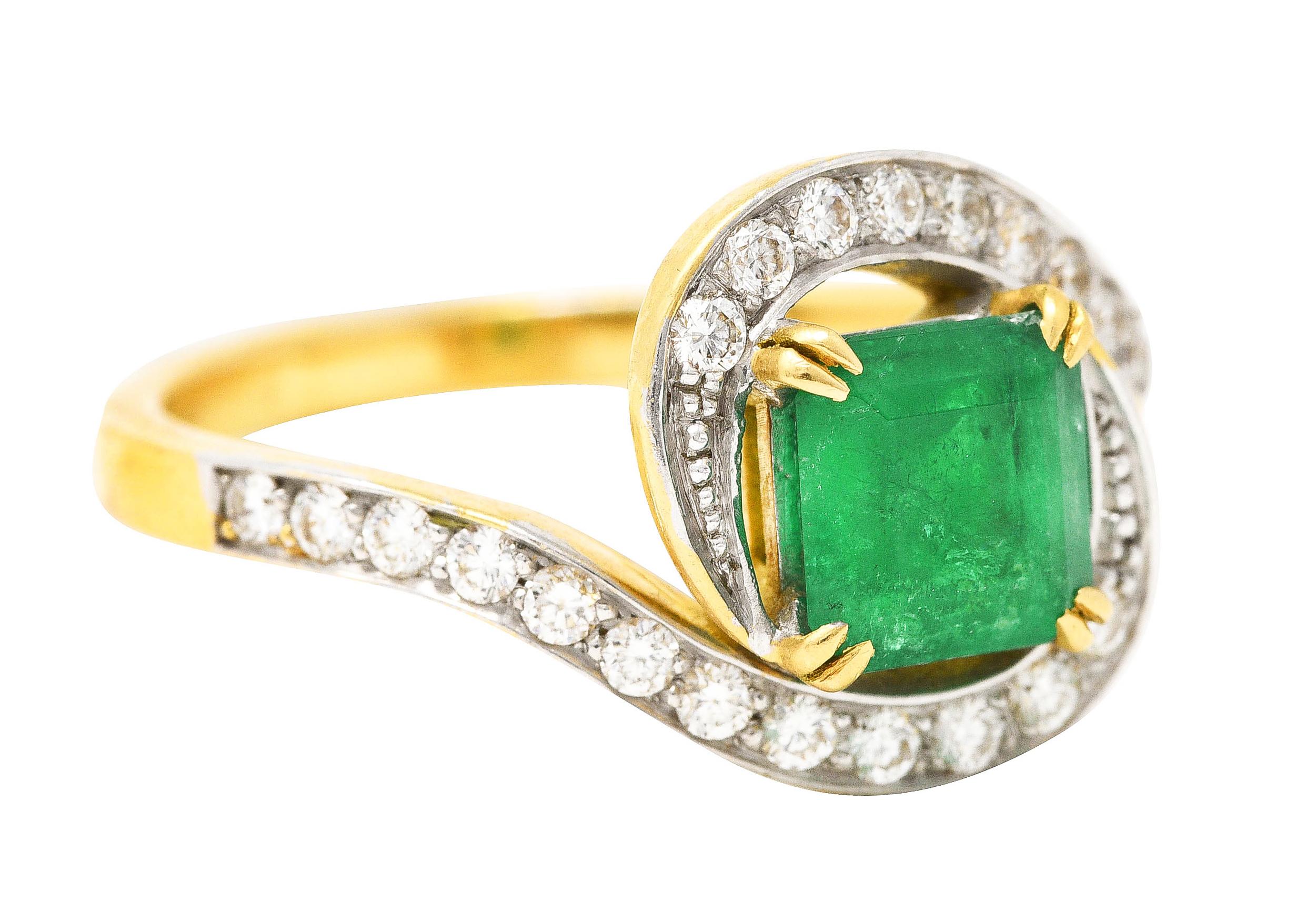 Featuring an emerald cut emerald weighing approximately 1.07 carats

Bright and uniformly green in color and translucent with natural inclusions

Basket set with split prongs and surrounded by scrolling bypass shoulders

Accented by round brilliant