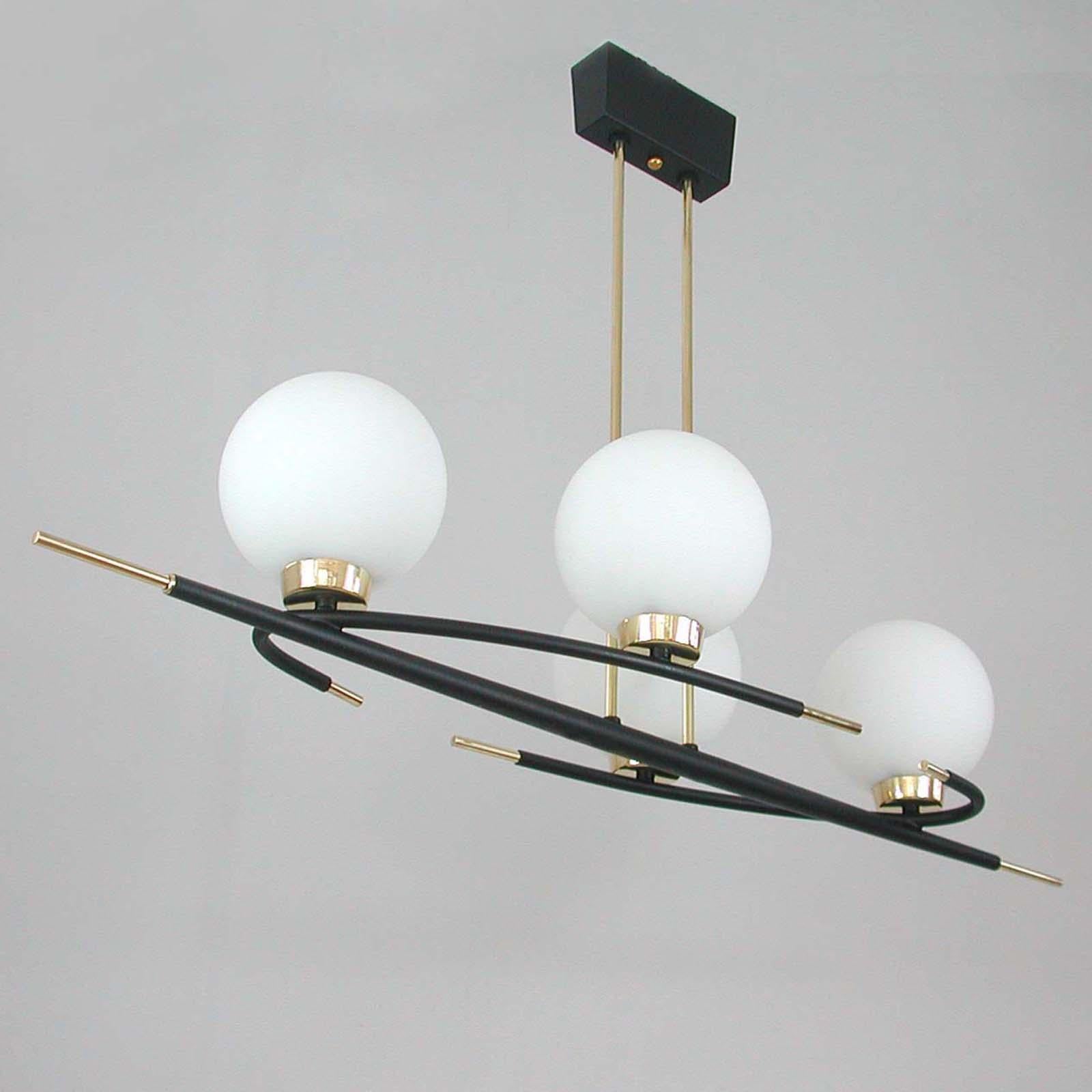 This unusual Maison Arlus ceiling light was designed and manufactured in France in the 1960s. It is made of black lacquered metal and brass with 4 white frosted glass lamp shades. 

The lamp requires 4 French B22 bayonet bulbs. Bulbs will be added