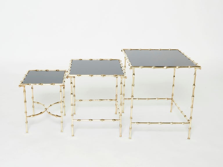 This beautiful set of nesting tables by French house Maison Baguès was created with solid bamboo shaped brass and beautiful black opaline glass tops circa 1960. The black tops are timeless and smooth, while the brass bamboo feet details provide an