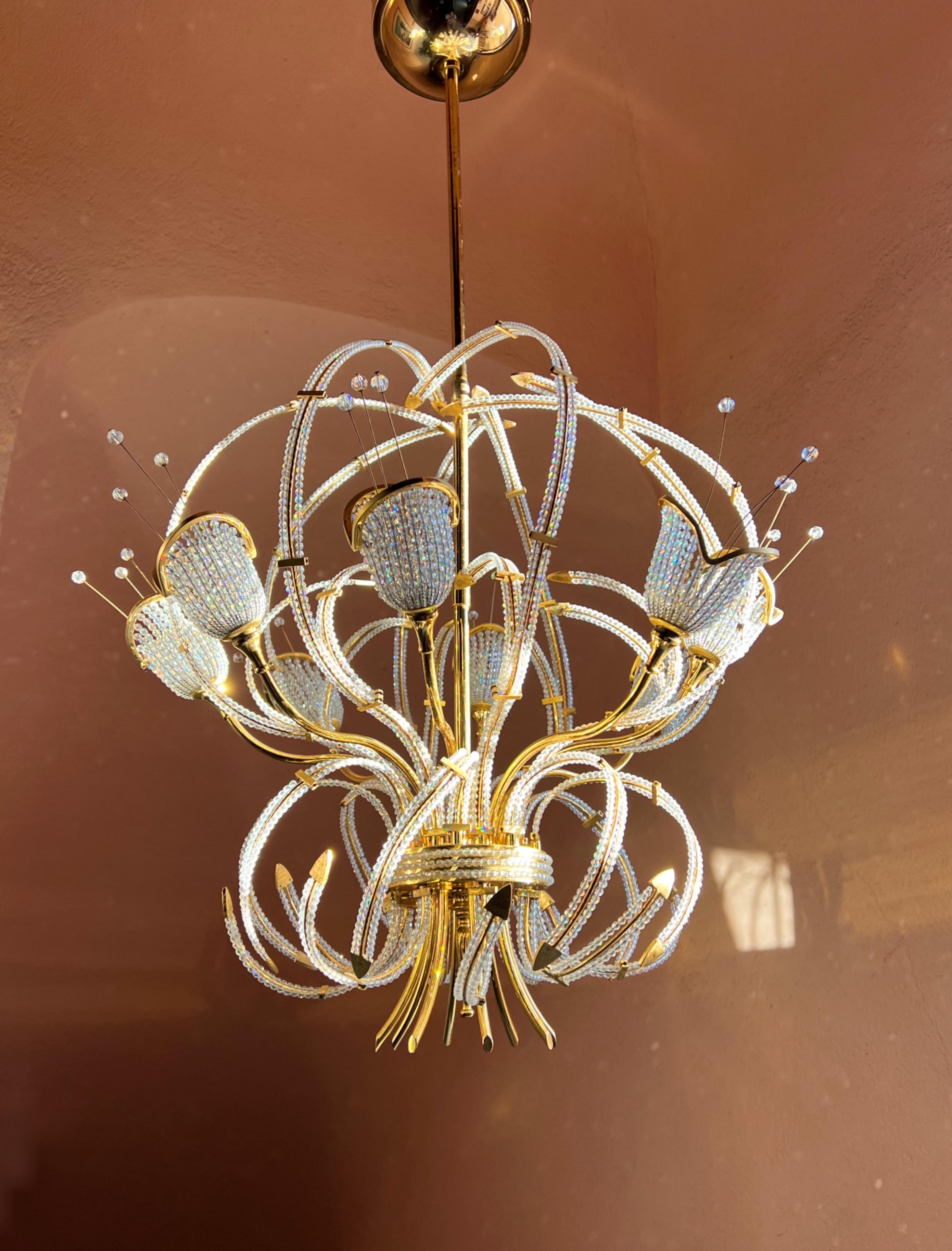 French Maison Bagues Beaded Crystal Chandelier. Made of brass and plated in 24k gold. Its design features graceful arms and decorative flowers in the end, all accented with Swarovski crystals that scatter the light beautifully. Please note that each