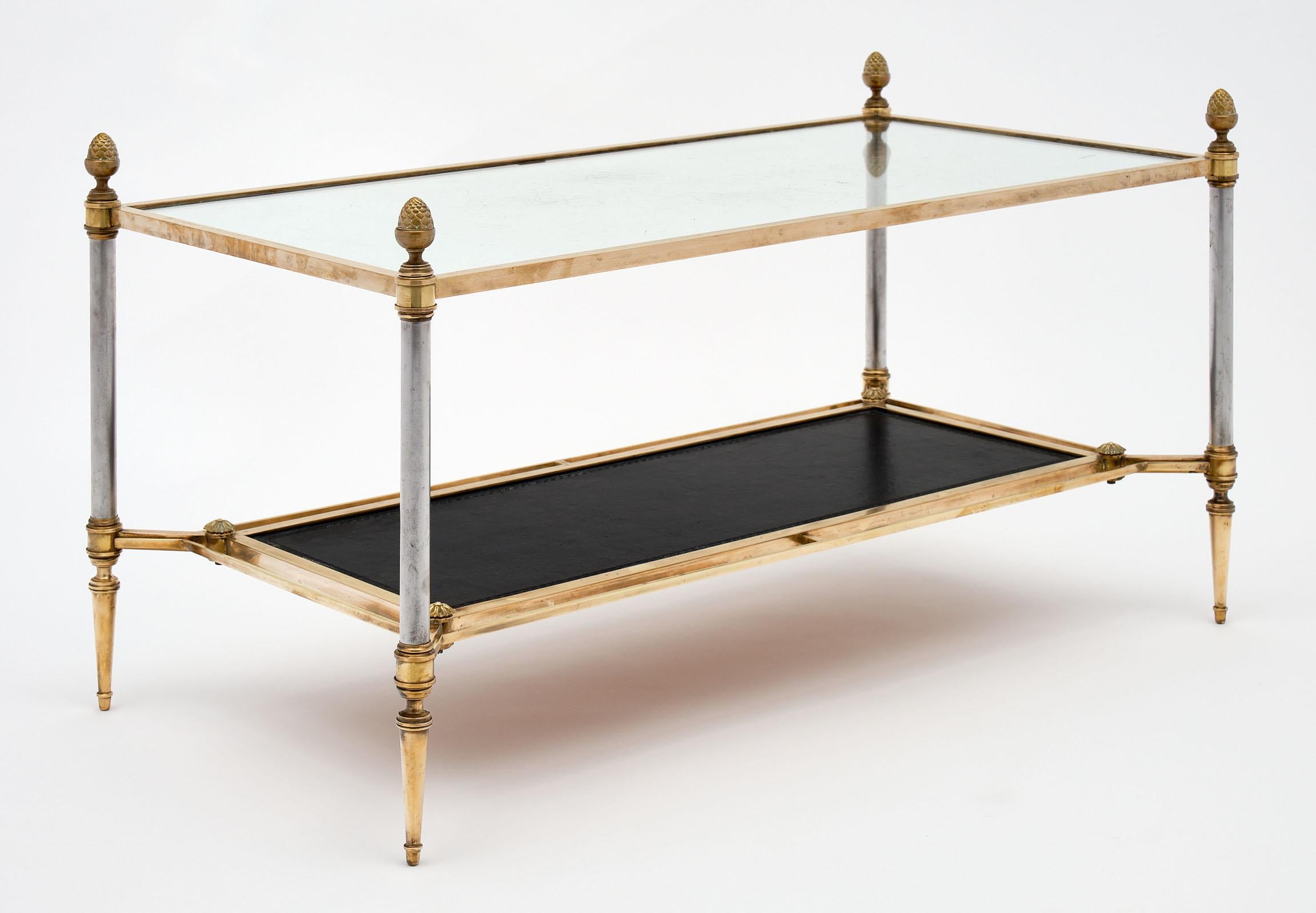 French Maison Baguès coffee table made of gilt bronze and steel. We love the finely cast details of acorns. This piece features a clear glass top and a black leather covered shelf.