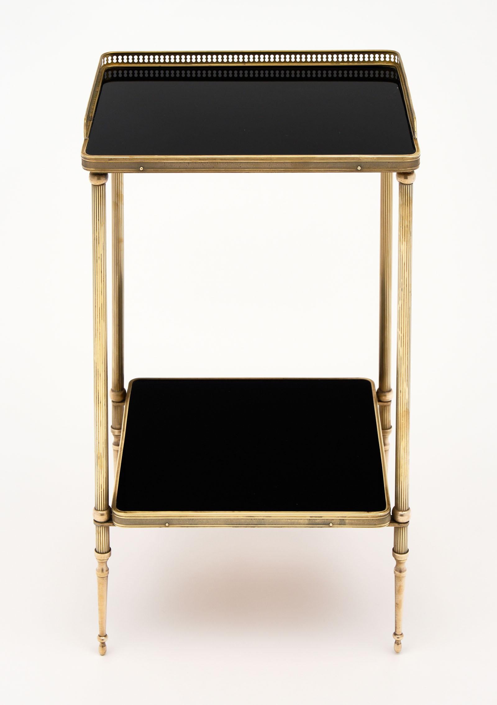 French Maison Baguès side table made with a polished brass structure and black glass top and shelf.