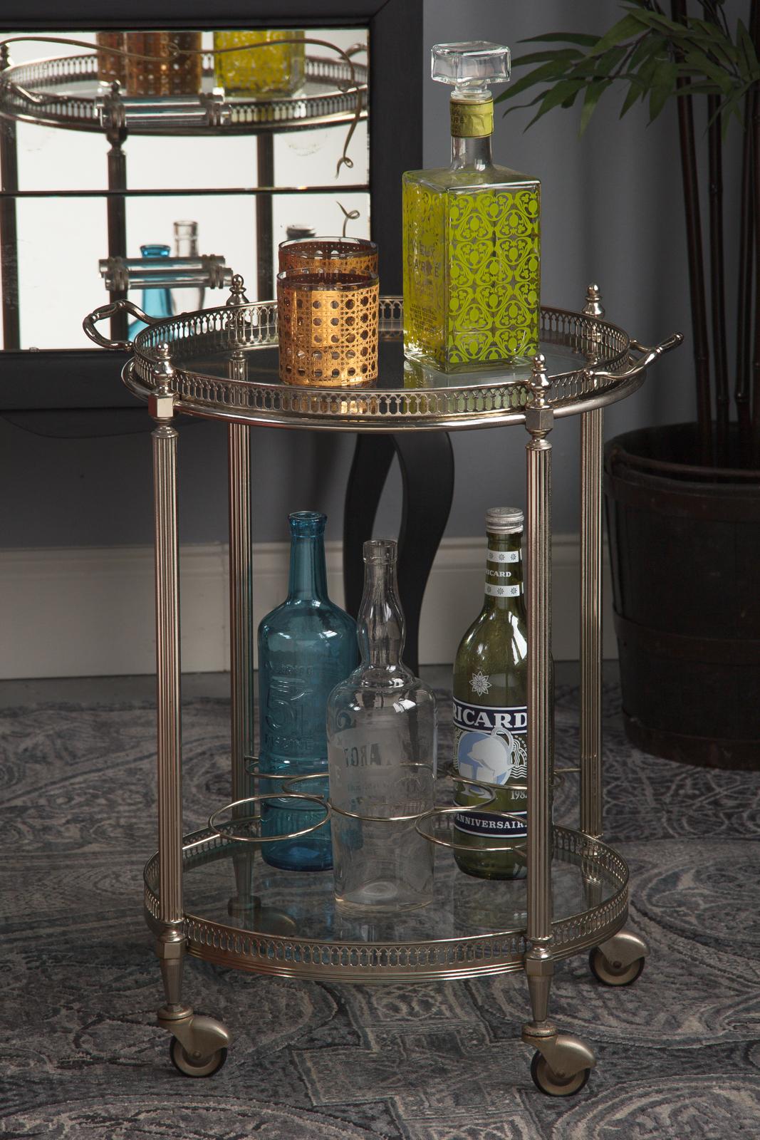 An elegant round silver metal French bar cart attributed to Maison Bagues, circa 1950. Polished silver metal throughout, having two tiers with glass trays, and four free-rolling rubber wheels. The top tray separates to carry drinks, etc. Both levels