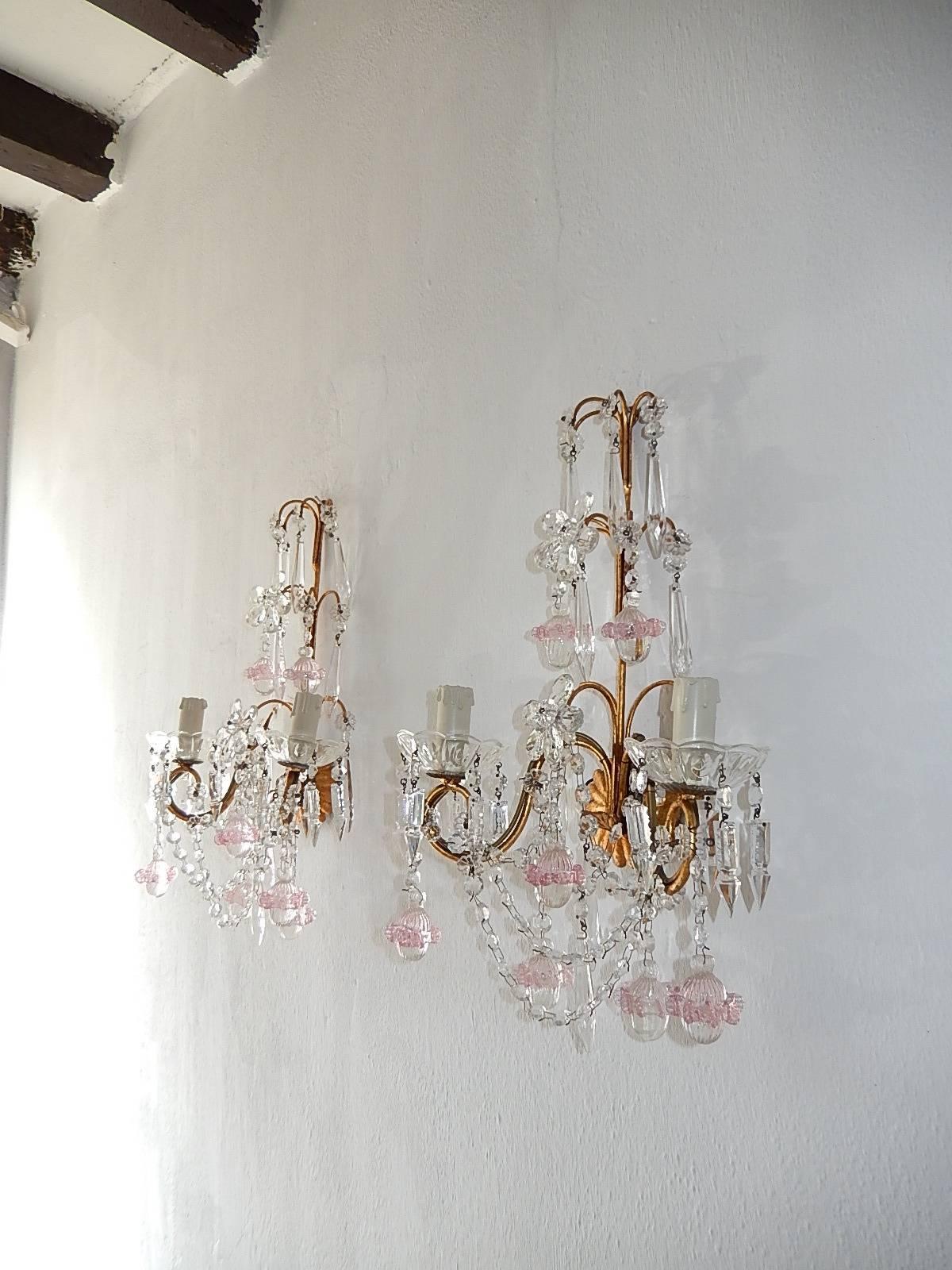 Housing two-light each. Will be rewired with certified US UL sockets for USA and appropriate sockets for all other countries and ready to hang.  Gilt metal body with crystal prisms and flower in center. Adorning Murano glass ribbed balls with pink