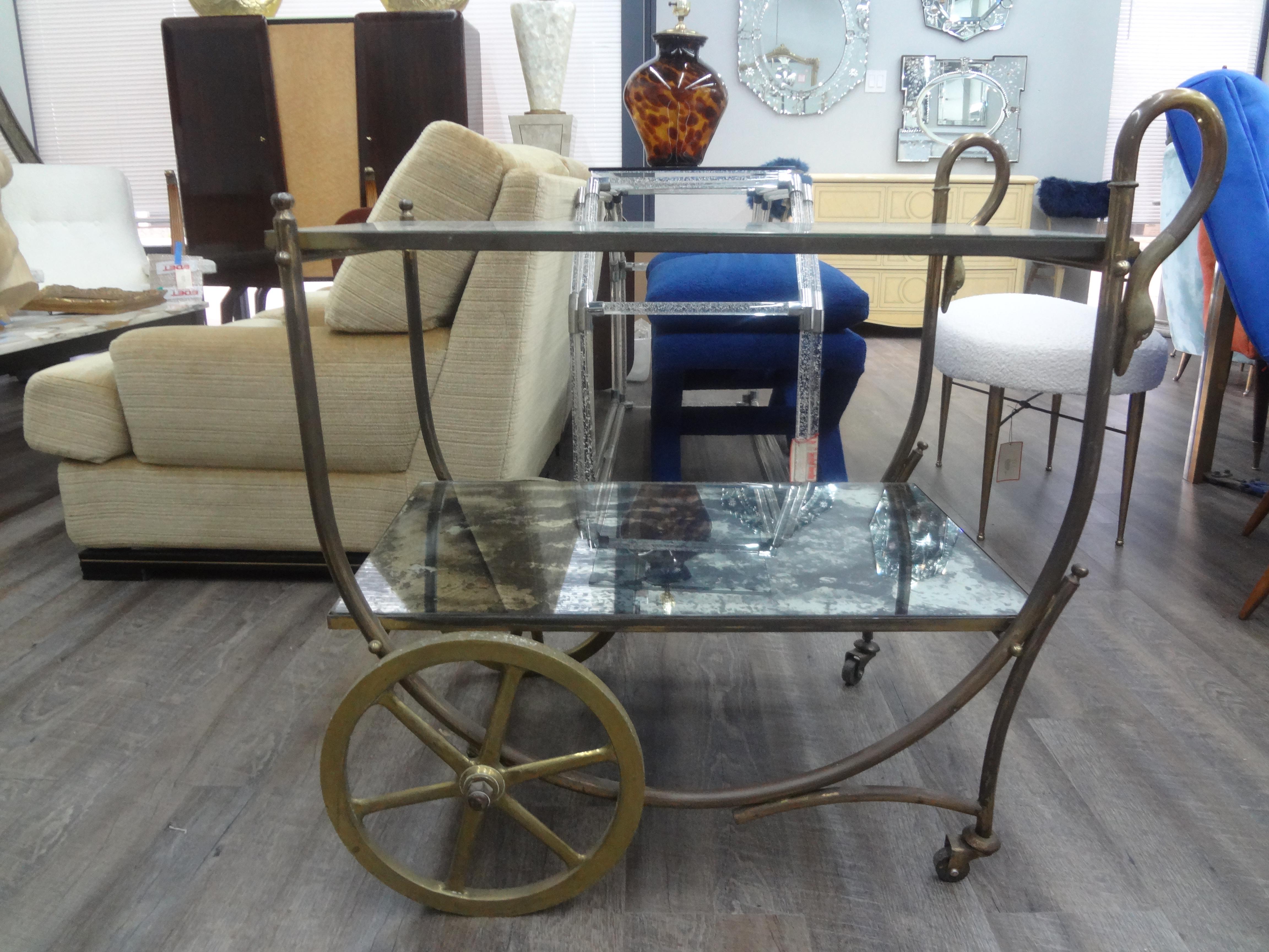French Maison Jansen attributed Neoclassical style bronze bar cart.
This stunning French Neoclassical style bronze bar cart has stunning large wheels, swan handles and two shelves with verre eglomisé (reverse decorated glass) tops.
Great bar cart or