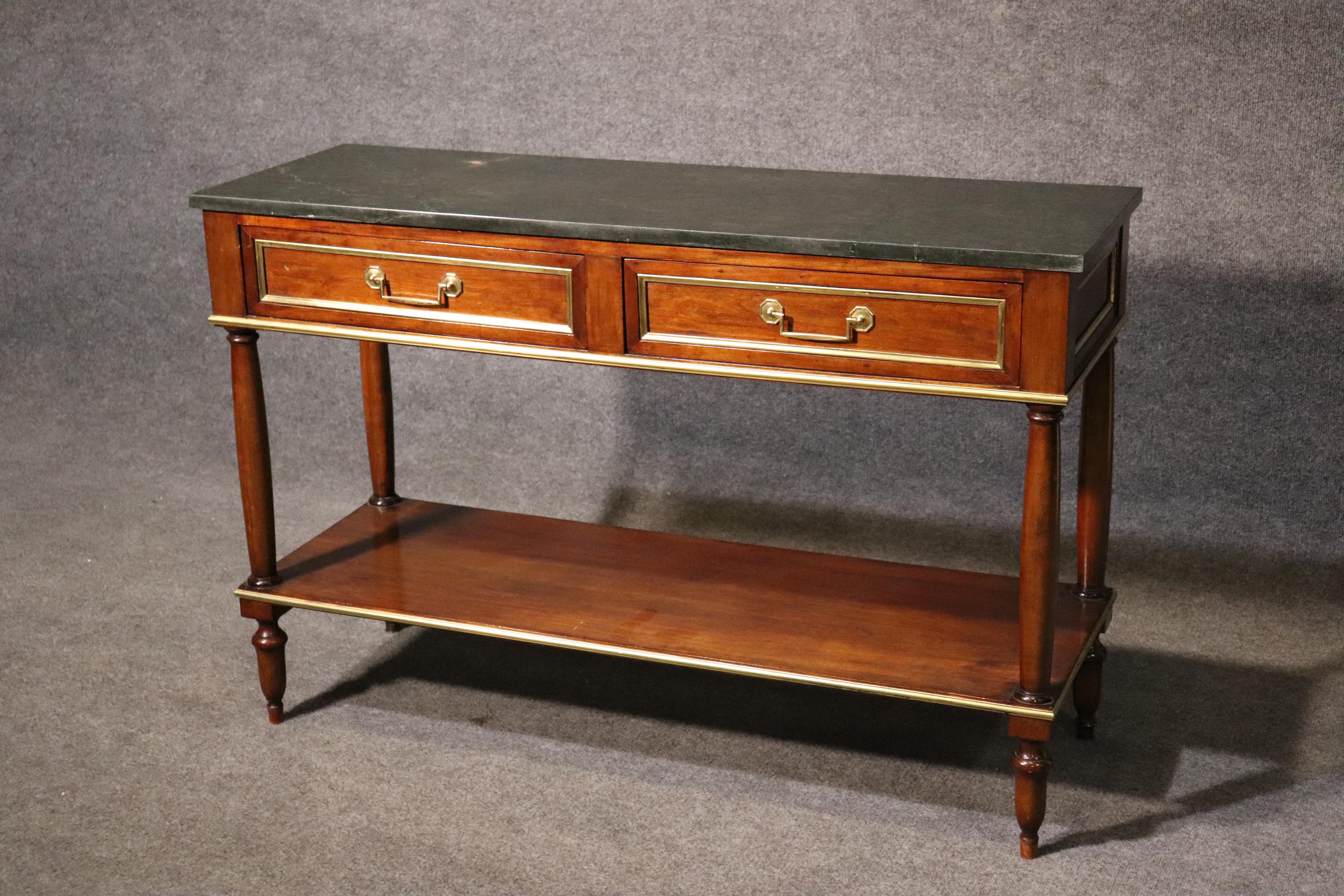 This is a gorgeous Maison Jansen attributed console table, circa 1940. Featuring the best verdi green marble top and fine brass trim, this console has the handsome lines of the Directoire period and a great mahogany case with dovetailed drawers. The